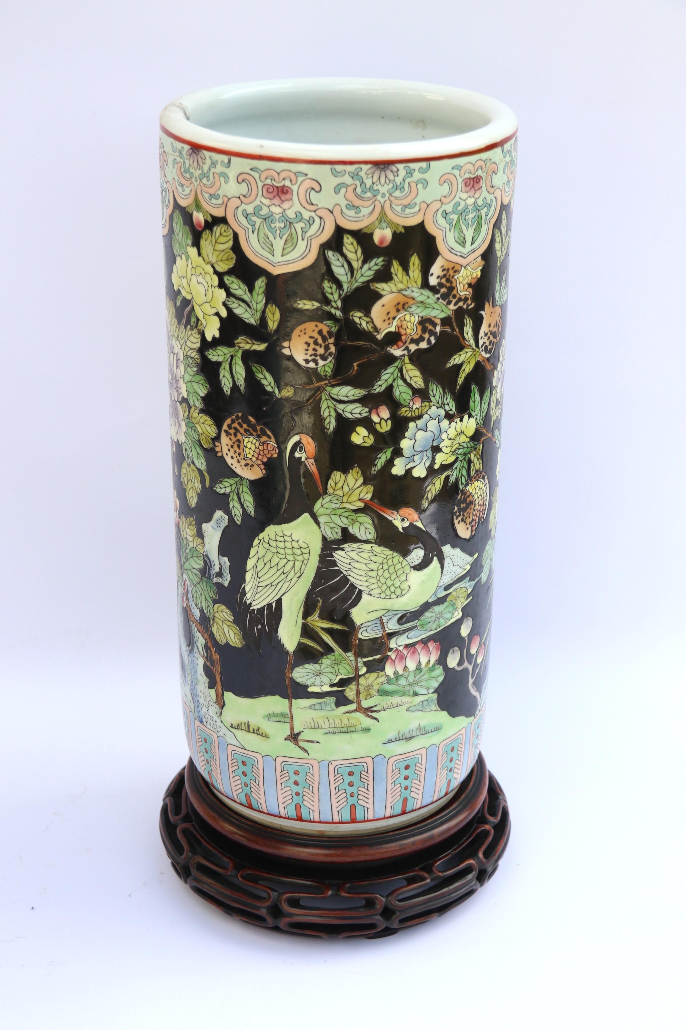 This most decorative large Chinese famille noire vase or possibly a walking stick stand dates to circa 1930 and it is richly decorated over a black enamel background (noire) with thick brightly coloured hand painted enamels with exotic birds,