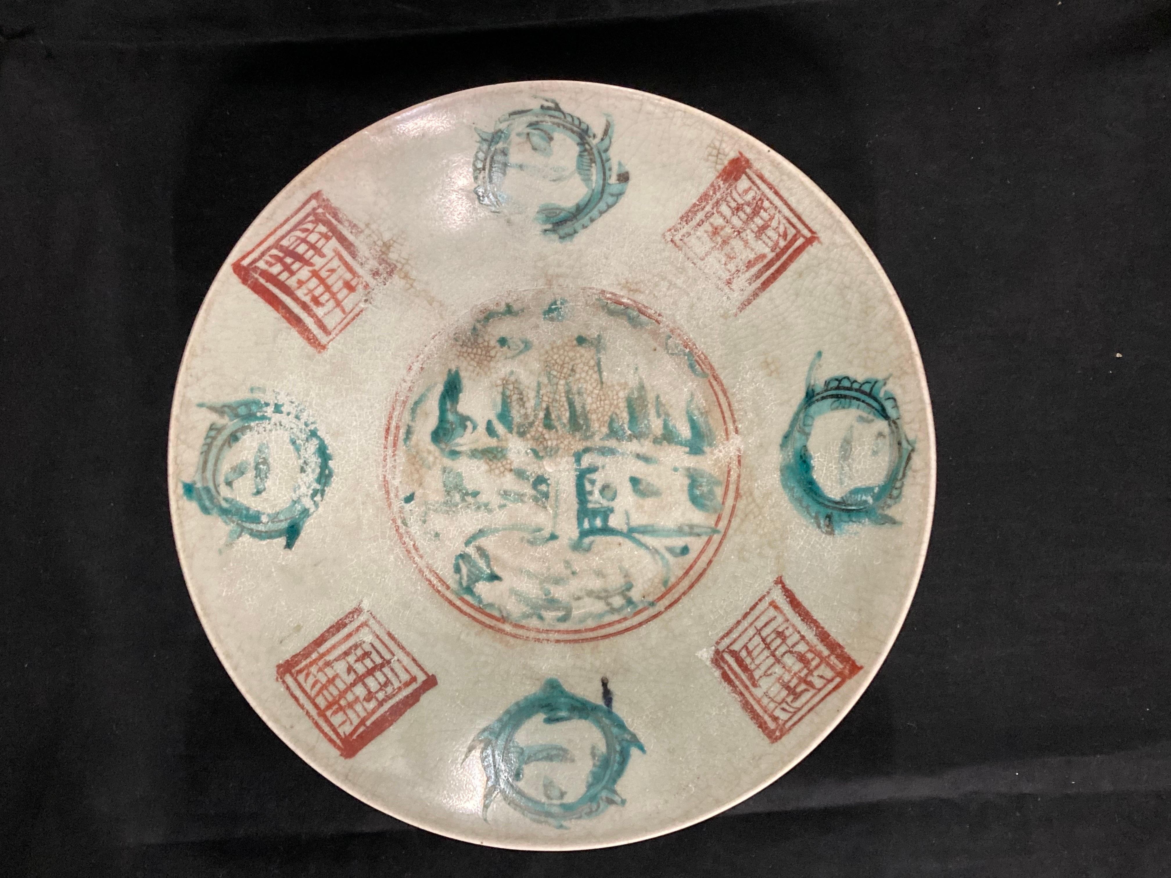 A large Chinese Ming Dynasty polychrome porcelain dish, circa 1620.

Late Ming Dynasty.
Painted in turquoise, black and red enamels with a central 'Split Pagoda' pattern scene, the cavetto with four landscape vignettes alternating with stylised