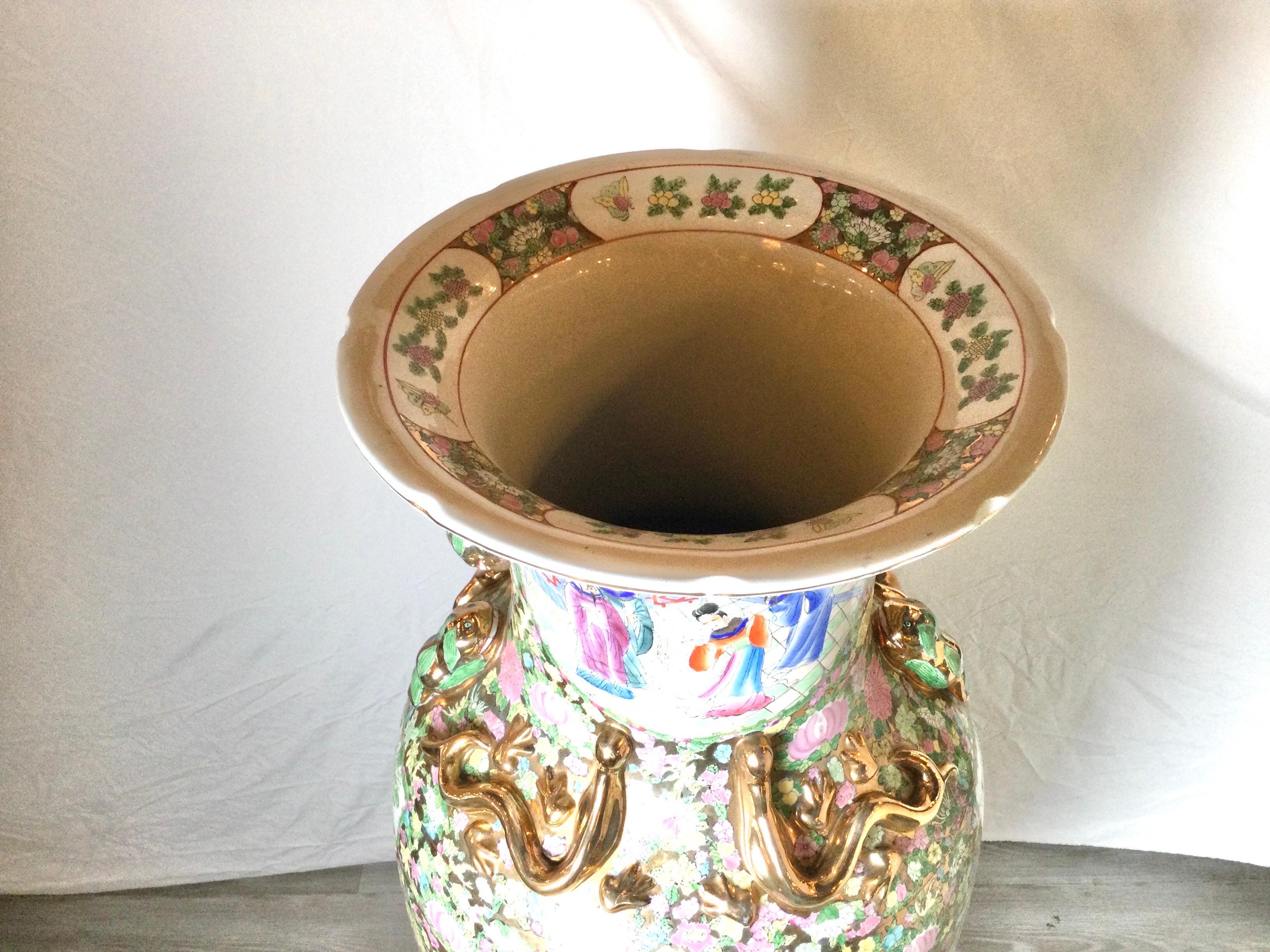 A monumental hand painted and gilt Chinese porcelain palace vase on wood stand. The white porcelain with large cartouches of well dressed noblemen surrounded by vibrant floral with gilt accents. The vase alone is 42.5 inches tall, 19 inches diameter