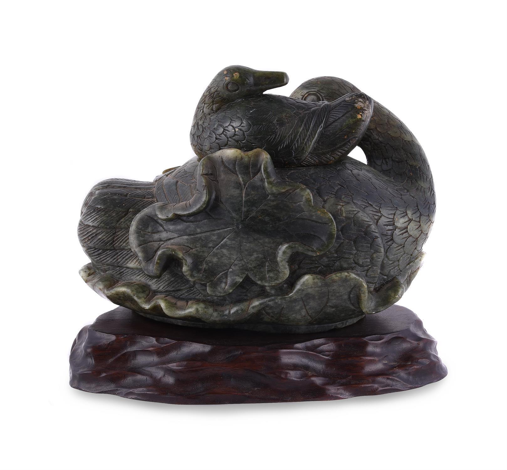 A large Chinese spinach jade duck carving, Qing Dynasty, 
holding a lotus flower in her mouth, the interior hollow with detachable 'duckling' cover, with labels for the National Gallery of South Africa 1953 exhibition, BADA and Radcliffe collection,