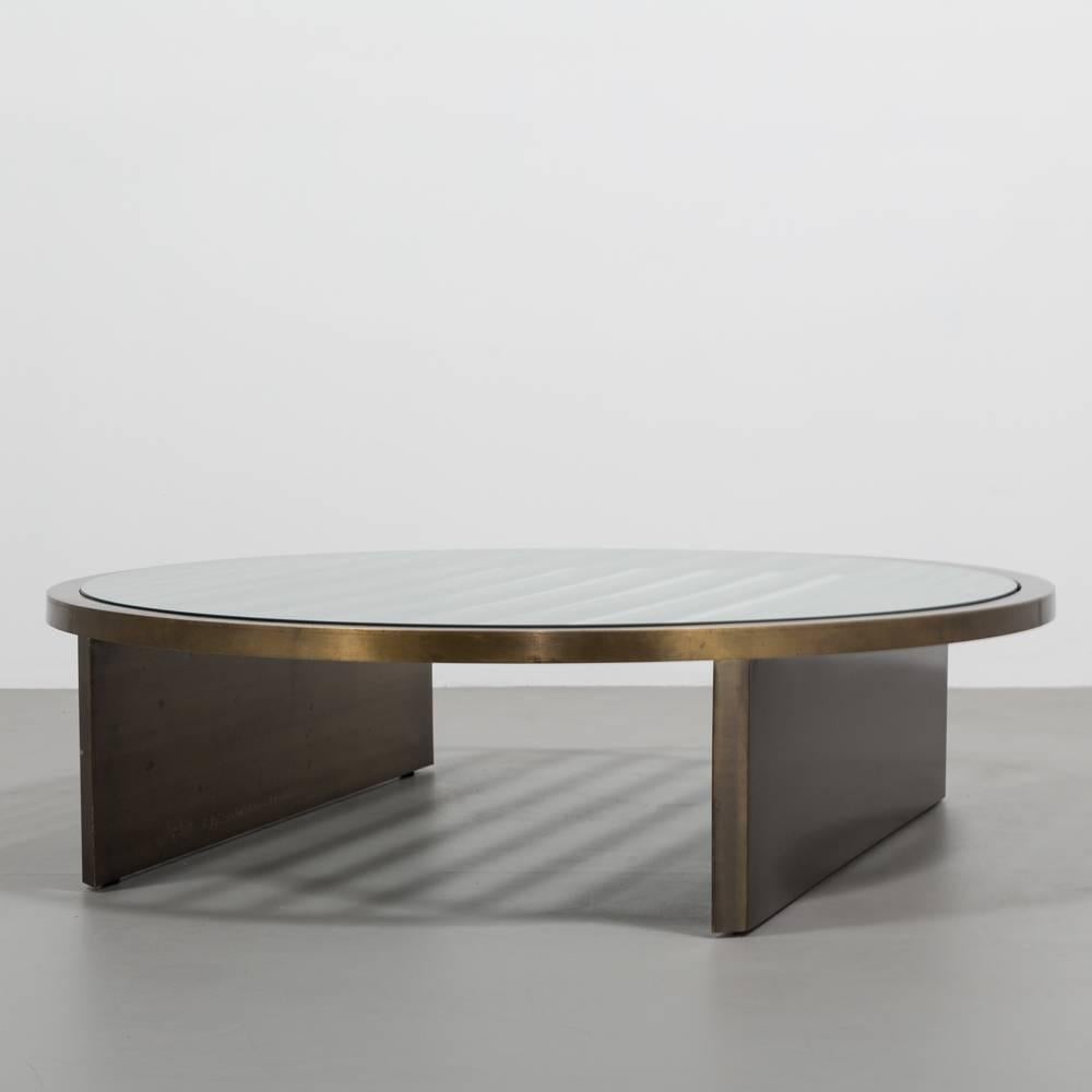 A large circular bronze framed coffee table with glass top, 1980s

The graphic pattern of graduated slats punctuated by the bold legs are really interesting details on this table and strongly sets it apart. The bronze has a great depth in tone and