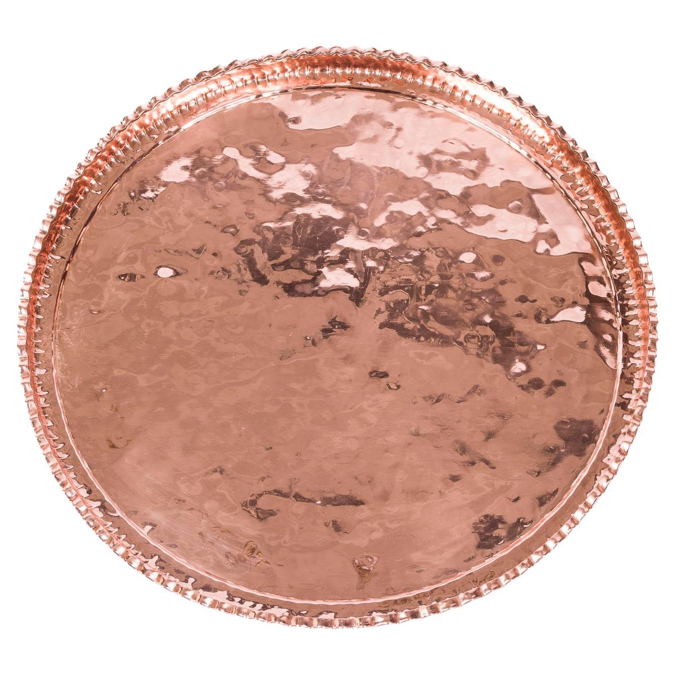 A large circular copper tray with pie crust edge