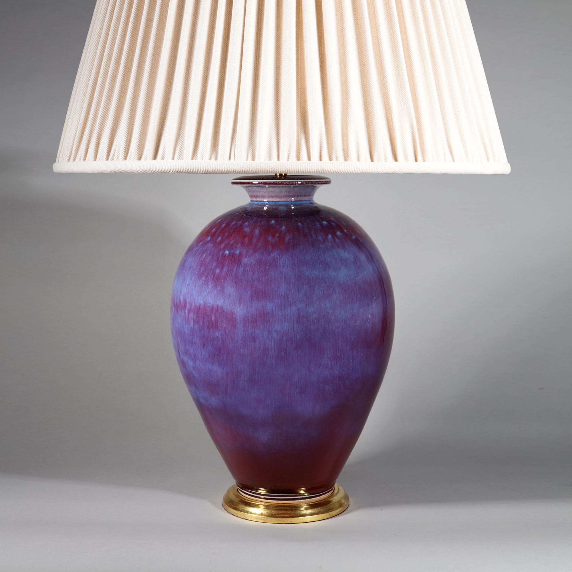 The voluptuous body of the vase of bulbous form, rising to broad shoulders and a short flared neck. The vase is covered in a stunning and complex vitreous oxblood red glaze, with areas of transmutation purple and blue (flambé). Now mounted on a