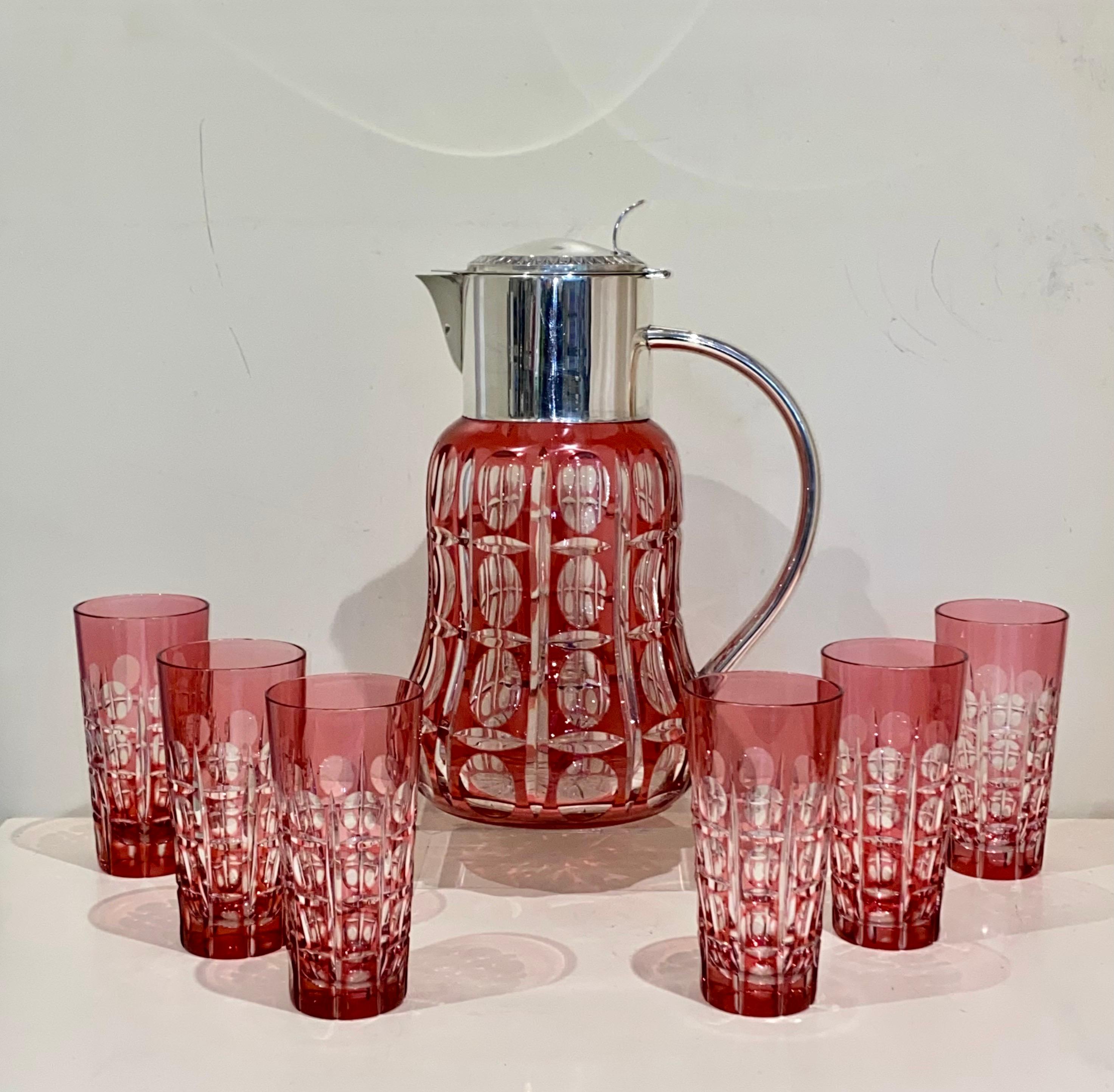 A large cranberry red overlay and cut to clear matching glass set with silver plated mounts. This is a fine quality group comprising nine individual pieces. A large jug with silver plated cover and handle, with removable ice tube, height 33cm. A