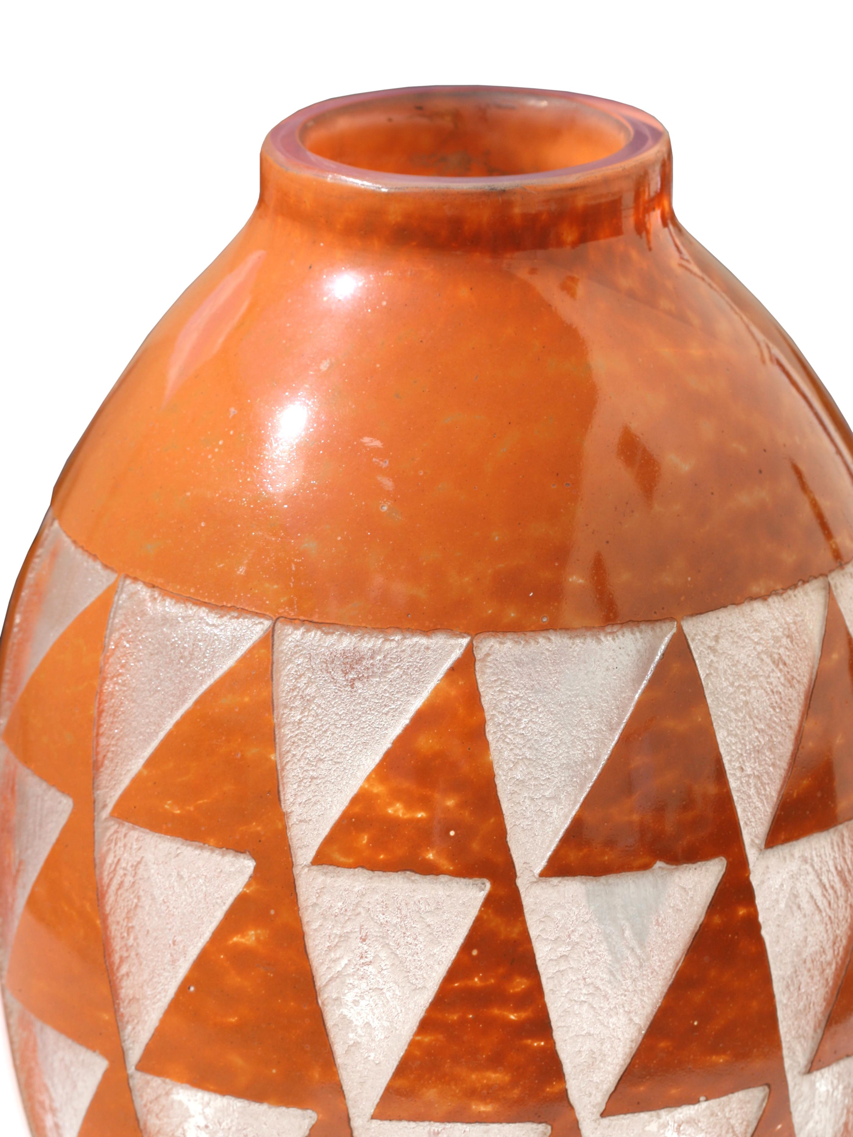 Un grand vase Degue en verre gravé à l'acide Art Déco, en verre de couleur orange de forme ovoïde, l'extérieur gravé de triangles stylisés sur une base circulaire, signé sur le bord, Degue.
Mesures : Hauteur : 41,9 cm (16,5 in.) 
Diamètre de 25,1