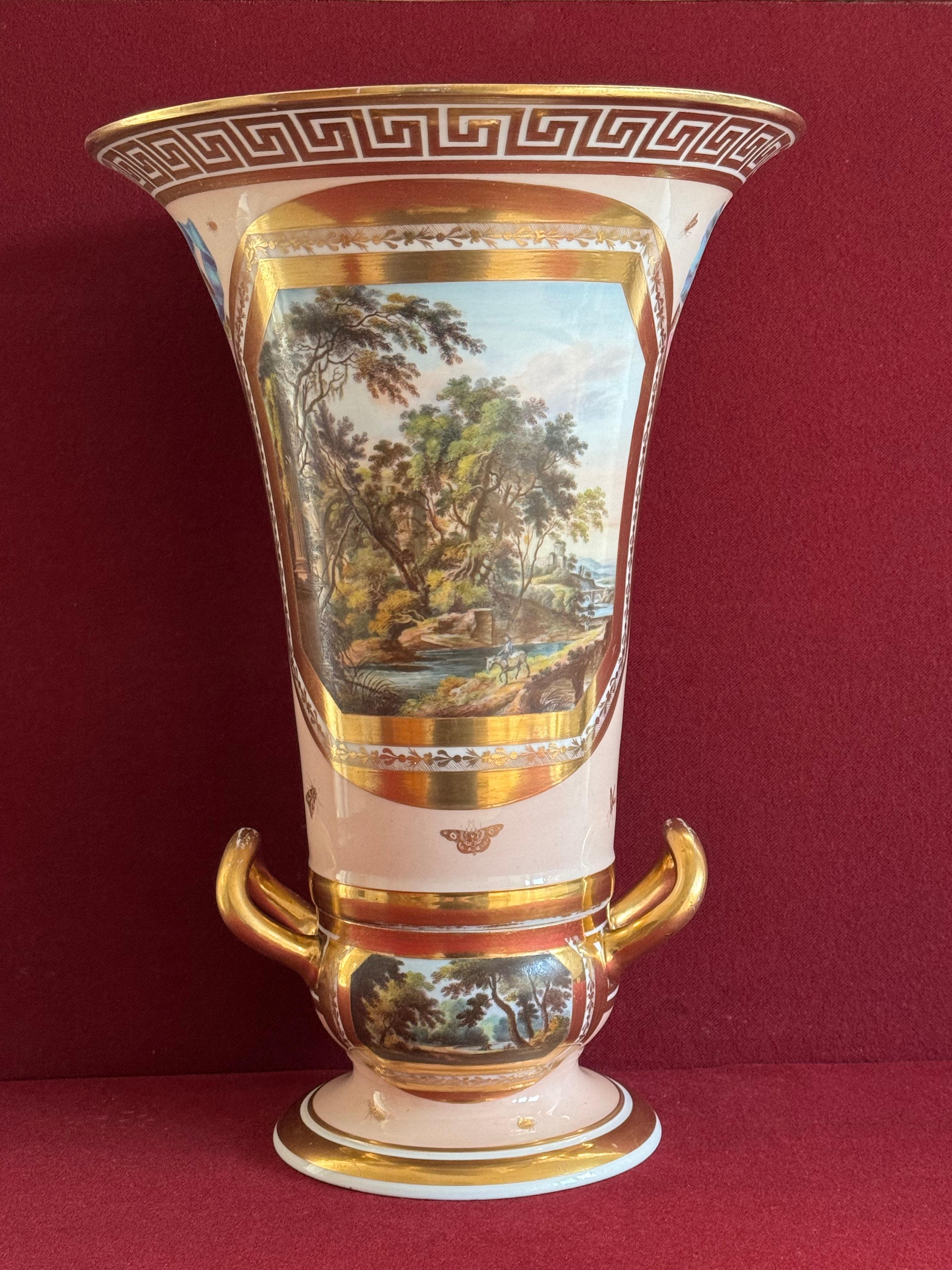 A large Derby porcelain two part vase c.1810. Very finely painted by John Brewer, with gilt framed panel, depicting a traveller riding a donkey before a river, in a woodland landscape. A ruined monastery, and a bridge in the background.
The reverse