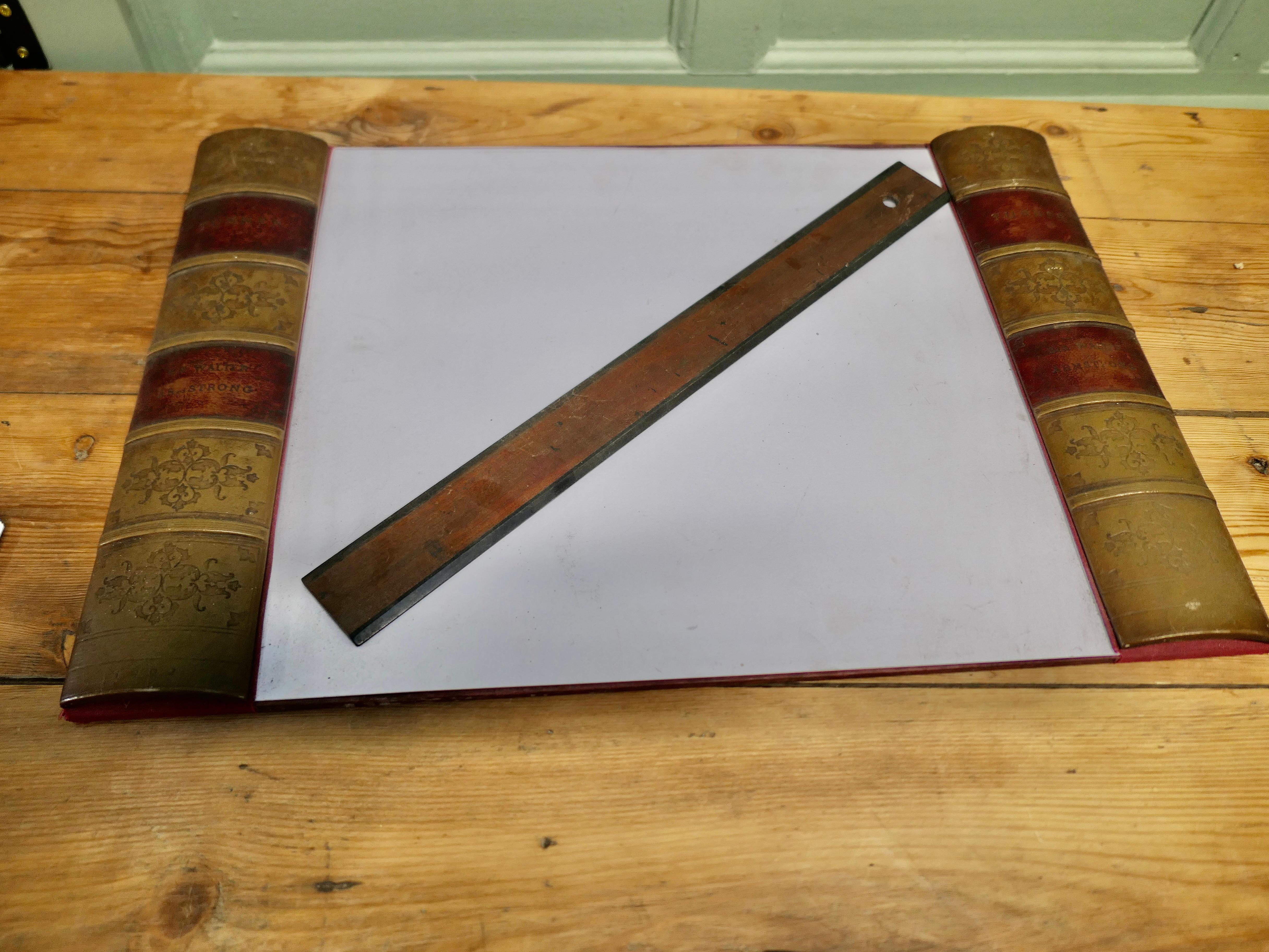 Ein großer Schreibtischblotter 

Die Schreibunterlage ist ein großartiges Möbelstück für den Schreibtisch. Sie hat simulierte Buchrücken in Gold und bordeauxfarbenem Leder und wird mit einem passenden Stanley-Lineal geliefert.
Der Blotter ist 15 