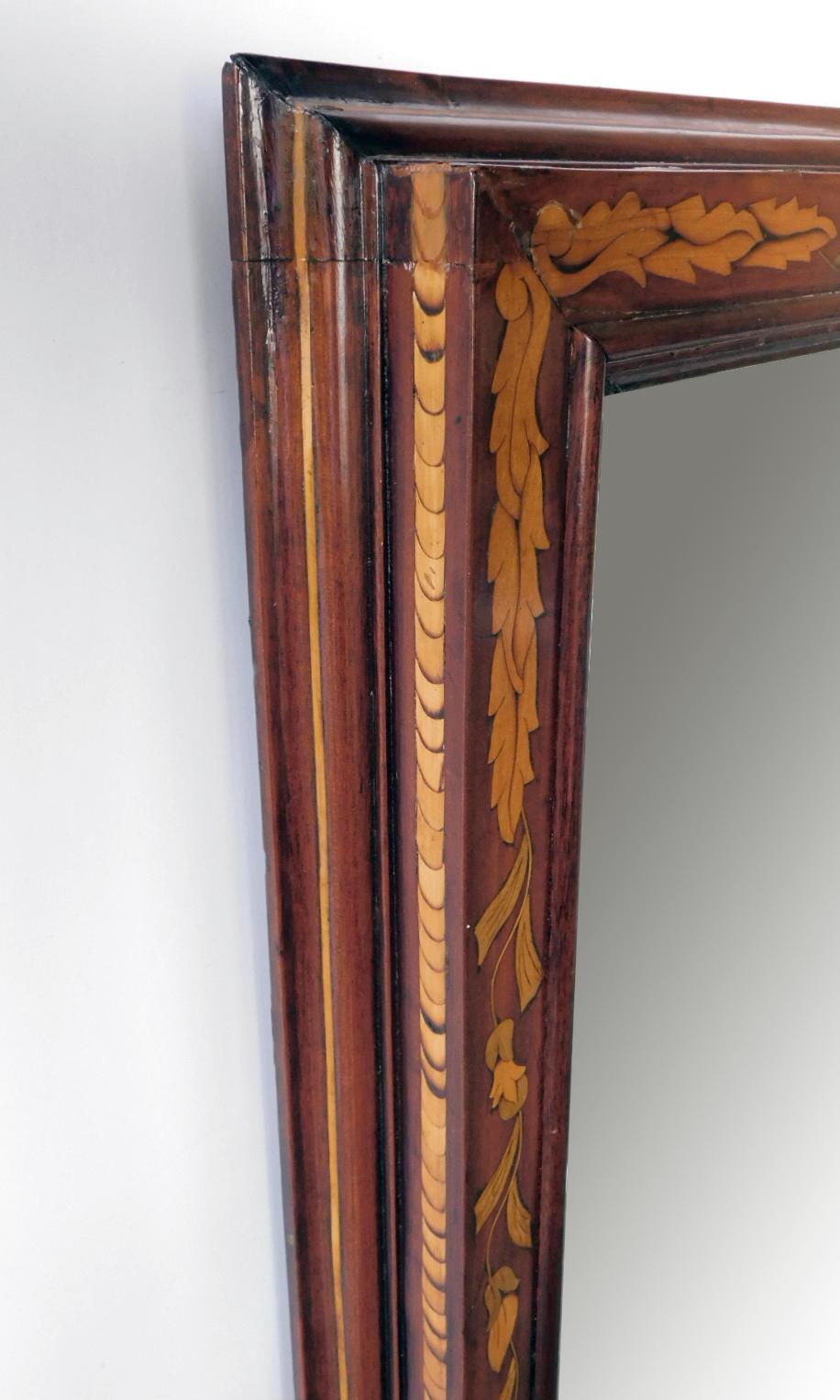 The mahogany ogee molded frame inlaid with a continuous boxwood floral and foliate marquetry vine.