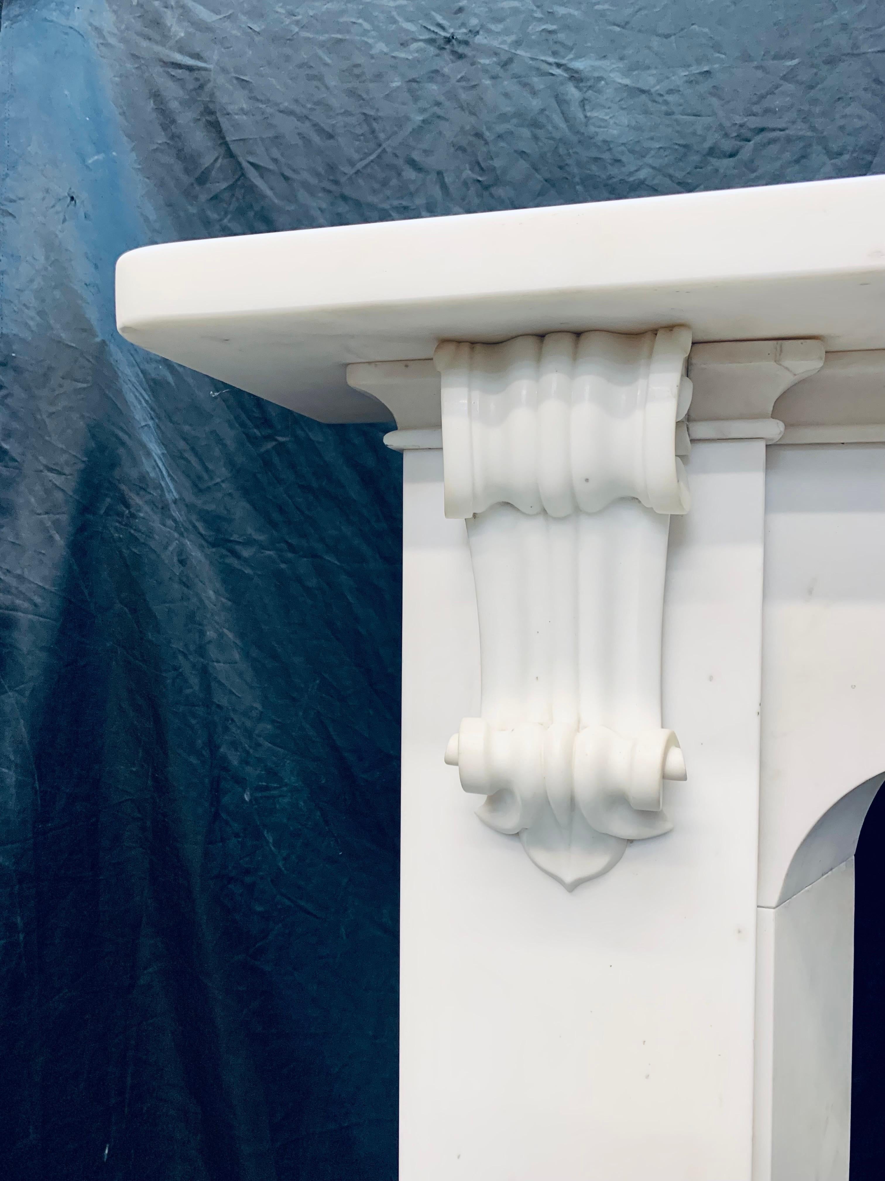 A large and elegant early 19th Century Scottish statuary marble Corbeled fireplace surround. A generous square edged top shelf, resting above a unadorned shaped frieze, flanked by tall and sturdy jambs with internal splayed returns, the external