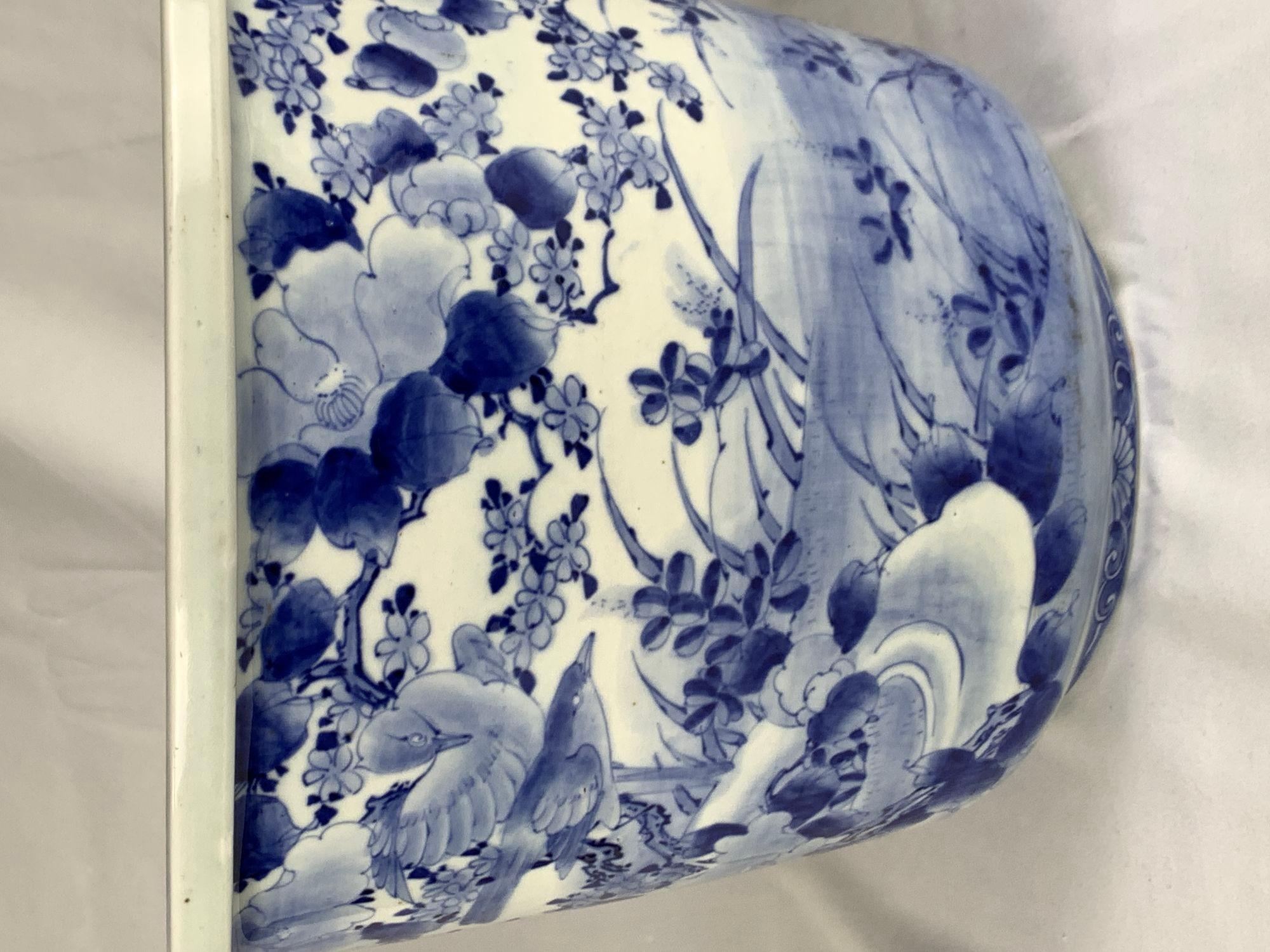 This large early 20th-century Japanese porcelain jardiniere with blue and white decoration is raised on three stub feet (see images).
The pot is decorated with a traditional scene of blossoming plum trees and a winding river with reeds and water