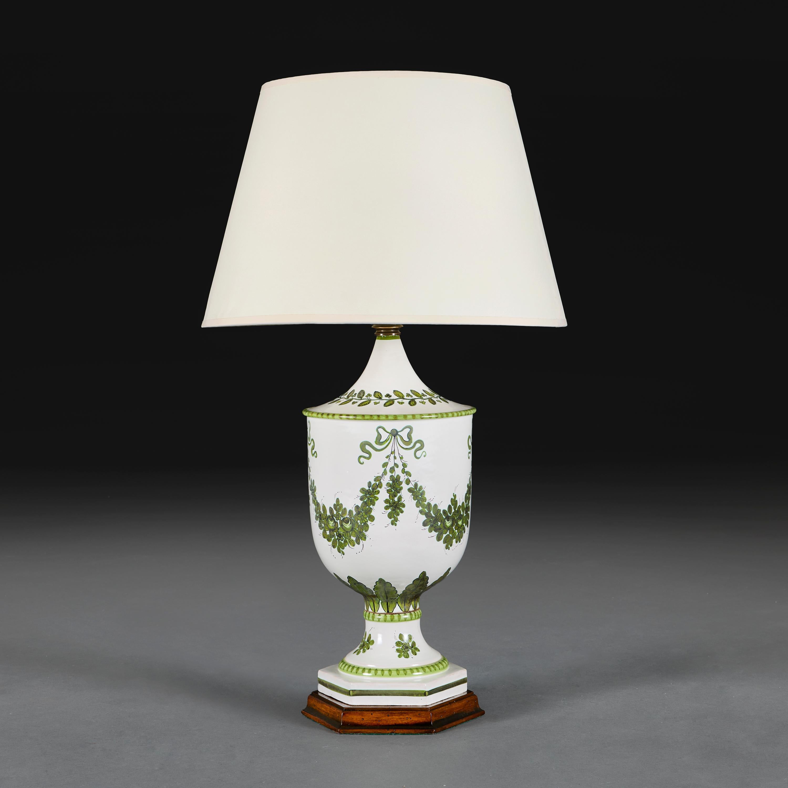 Inglaterra, hacia 1910.

Gran lámpara urna de cerámica eduardiana decorada con guirnaldas y lazos de follaje verde sobre fondo blanco, montada sobre una base hexagonal de nogal.

Altura 52,00 centímetros.
Anchura de la base 22,00 centímetros.

Tenga