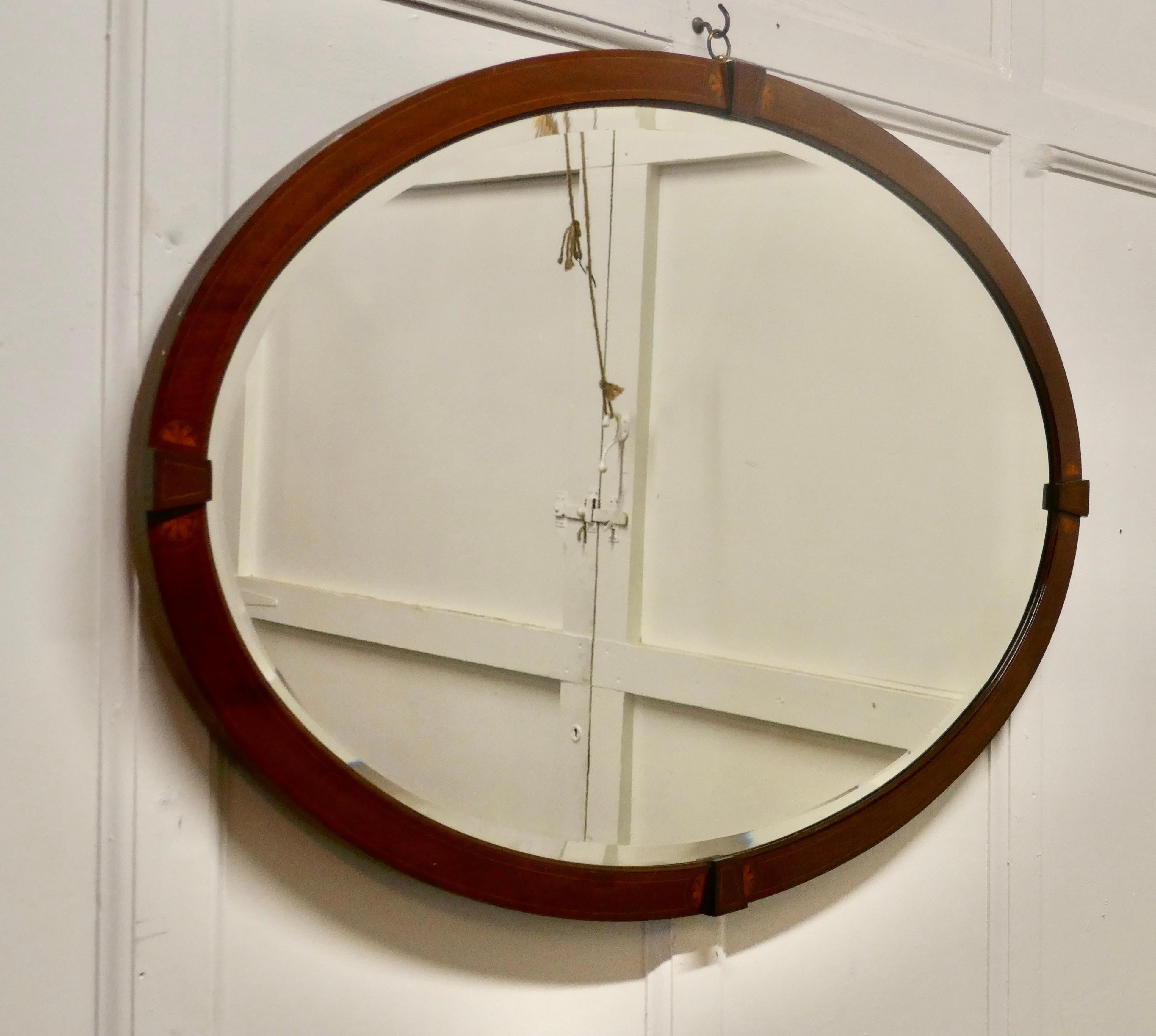 A large Edwardian Inlaid mahogany oval mirror.

This mirror has a 2” wide moulded mahogany frame which has a shell inlay
The large oval frame is in very good condition as is the original Oval bevelled looking glass 
The mirror is 38” wide and