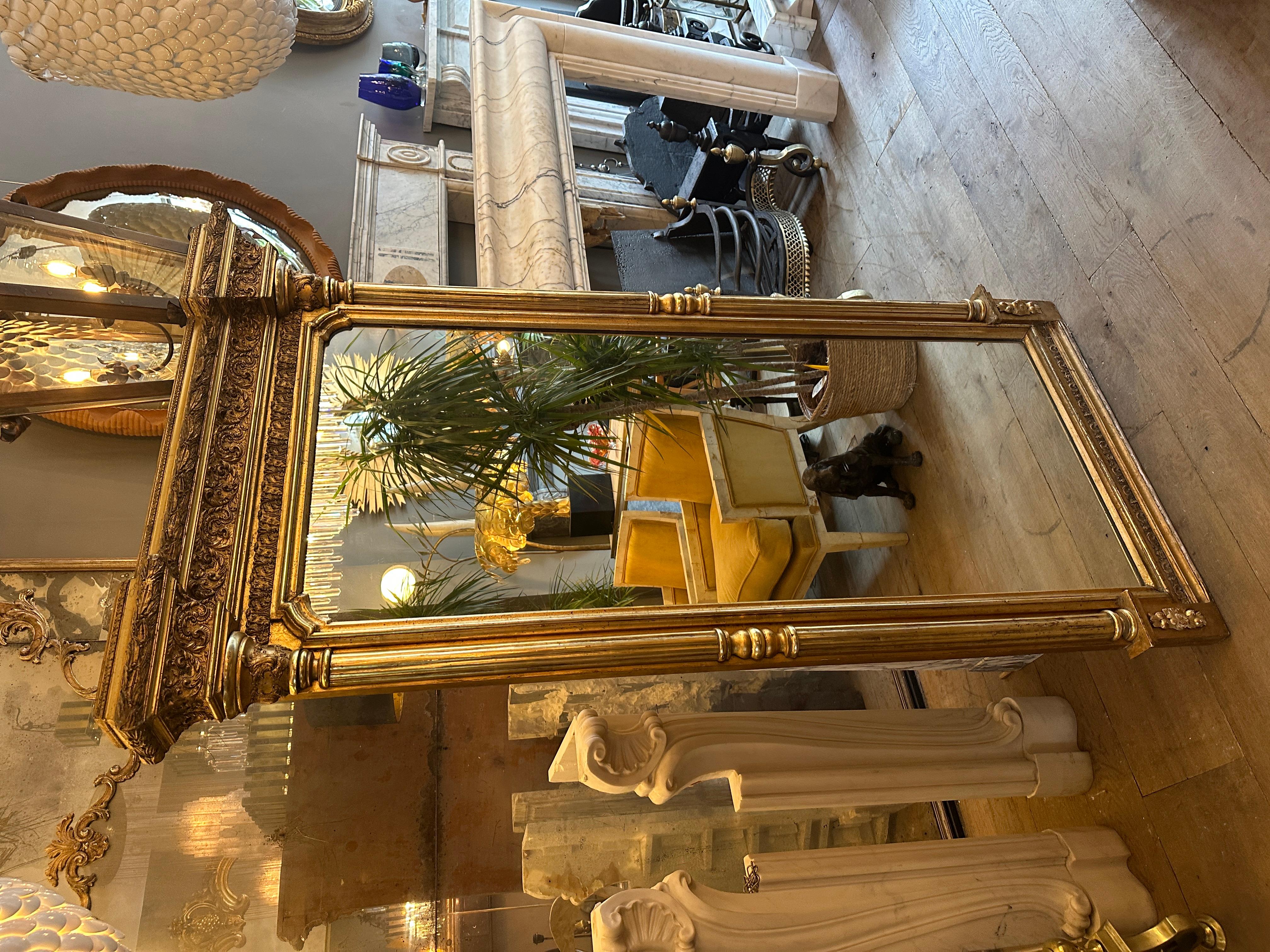A tall gold gilt and gesso English Regency Pier mirror glass. Very well and profusely decorated pediment, with columned uprights and capitals. Warm and soft patina and gilt work, mirror plate in good order with boarded back. Shaped inner slip to