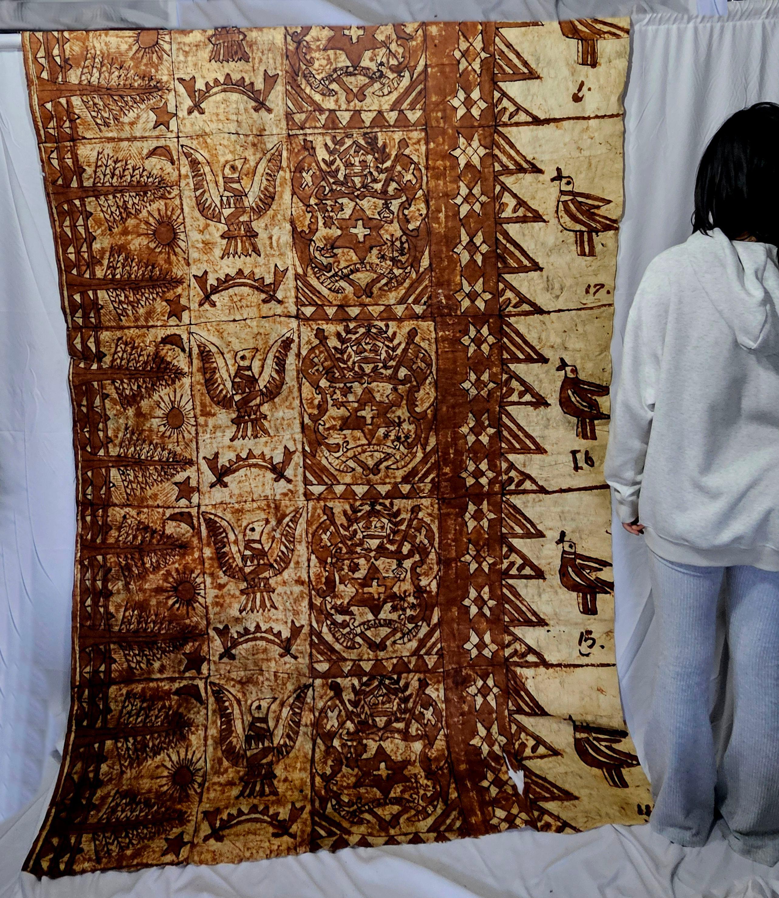 Beschreibung
Barkcloth, ngatu, aus Rinde (wahrscheinlich Papiermaulbeere). Rechteckiger, hellbrauner Stoff, der aus mit Tapioka zusammengeklebten Stoffteilen hergestellt wird. Die Dekoration ist in fünf vertikale und fünf horizontale Abschnitte