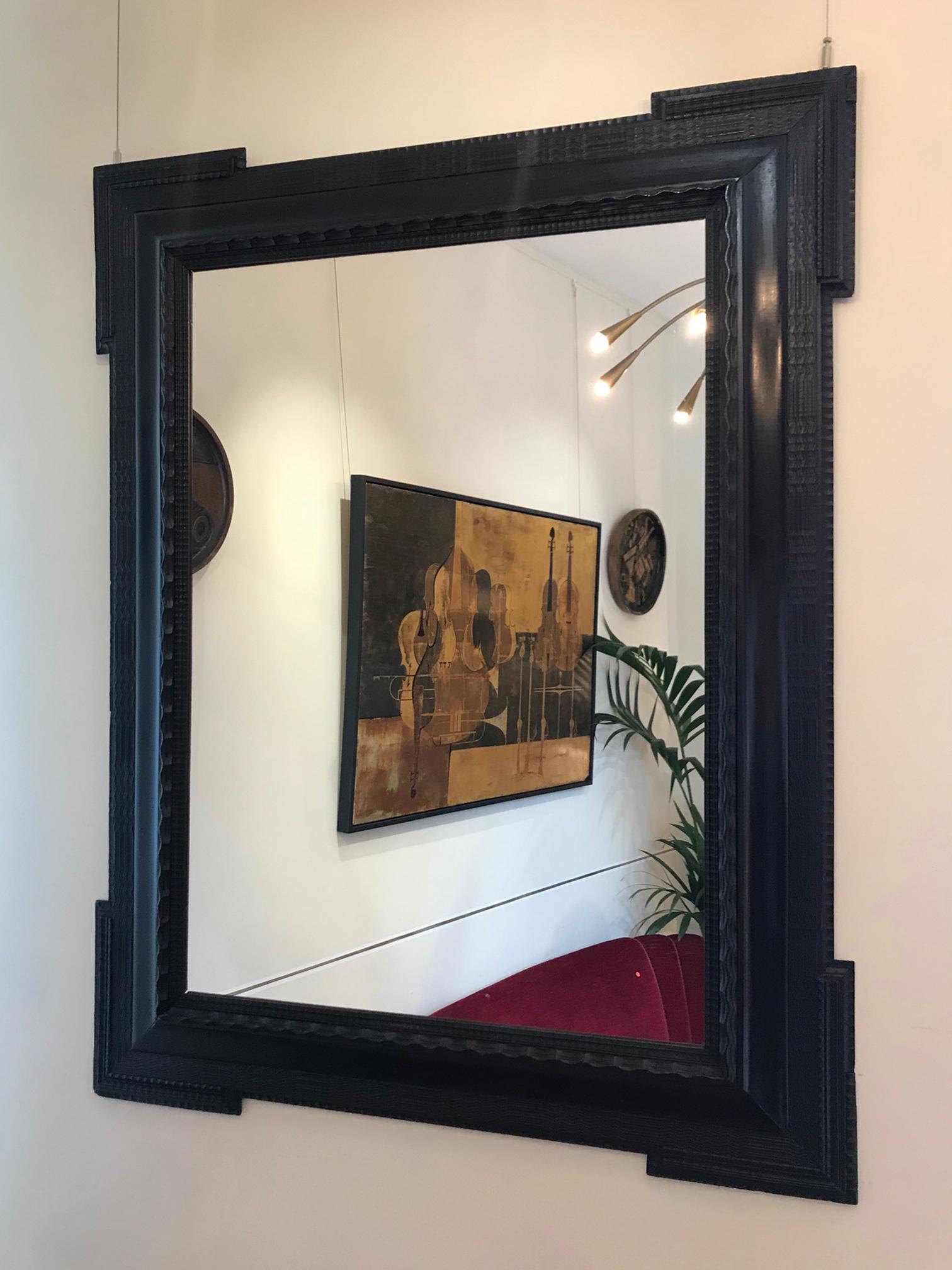 A large Flemish ebonised carved wood ripple frame mirror
Holland, circa 1920.