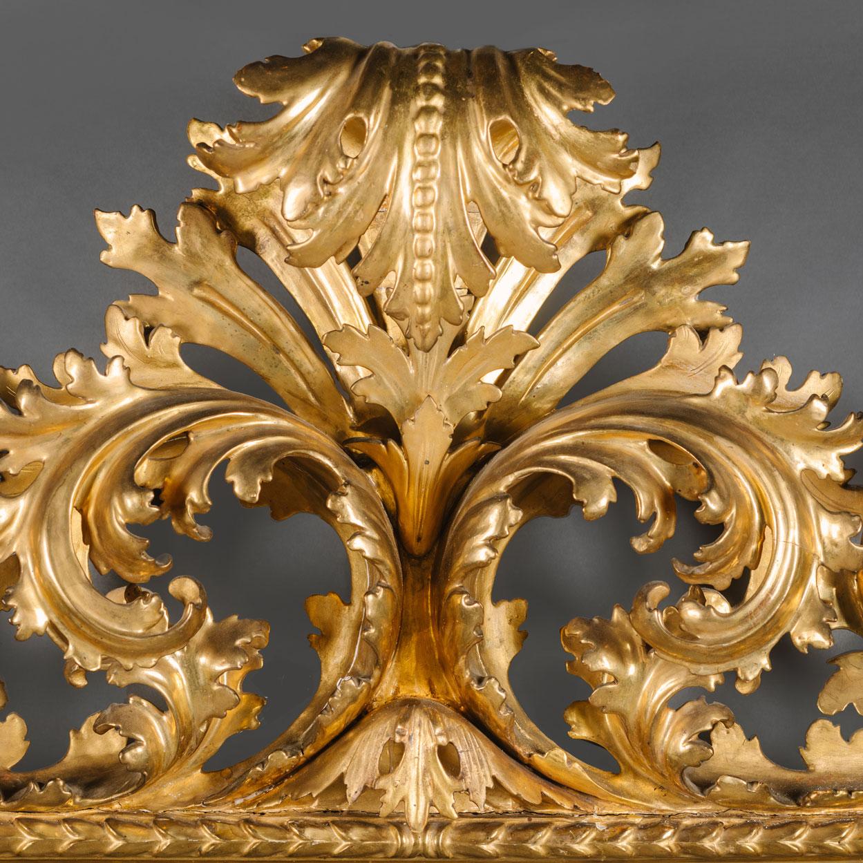 Un grand miroir en bois doré florentin sculpté dans le style néo-baroque. 

Cet impressionnant miroir présente une plaque de verre rectangulaire biseautée dans un cadre sculpté d'acanthe à volutes, avec une crête centrale d'acanthe frondée et un