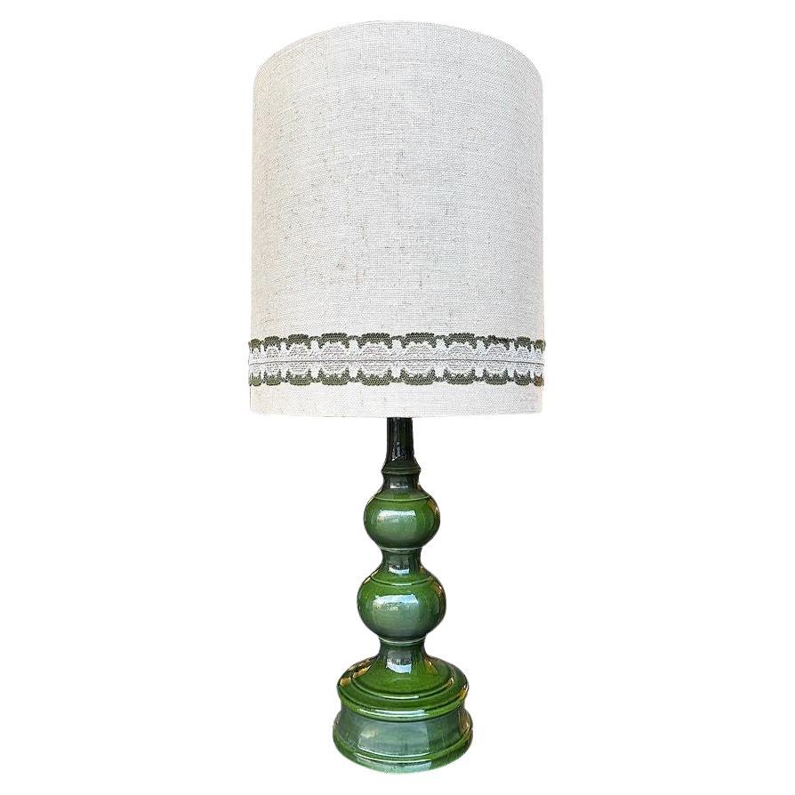 A large French 1960s green glazed ceramic lamp with original hessian shade
