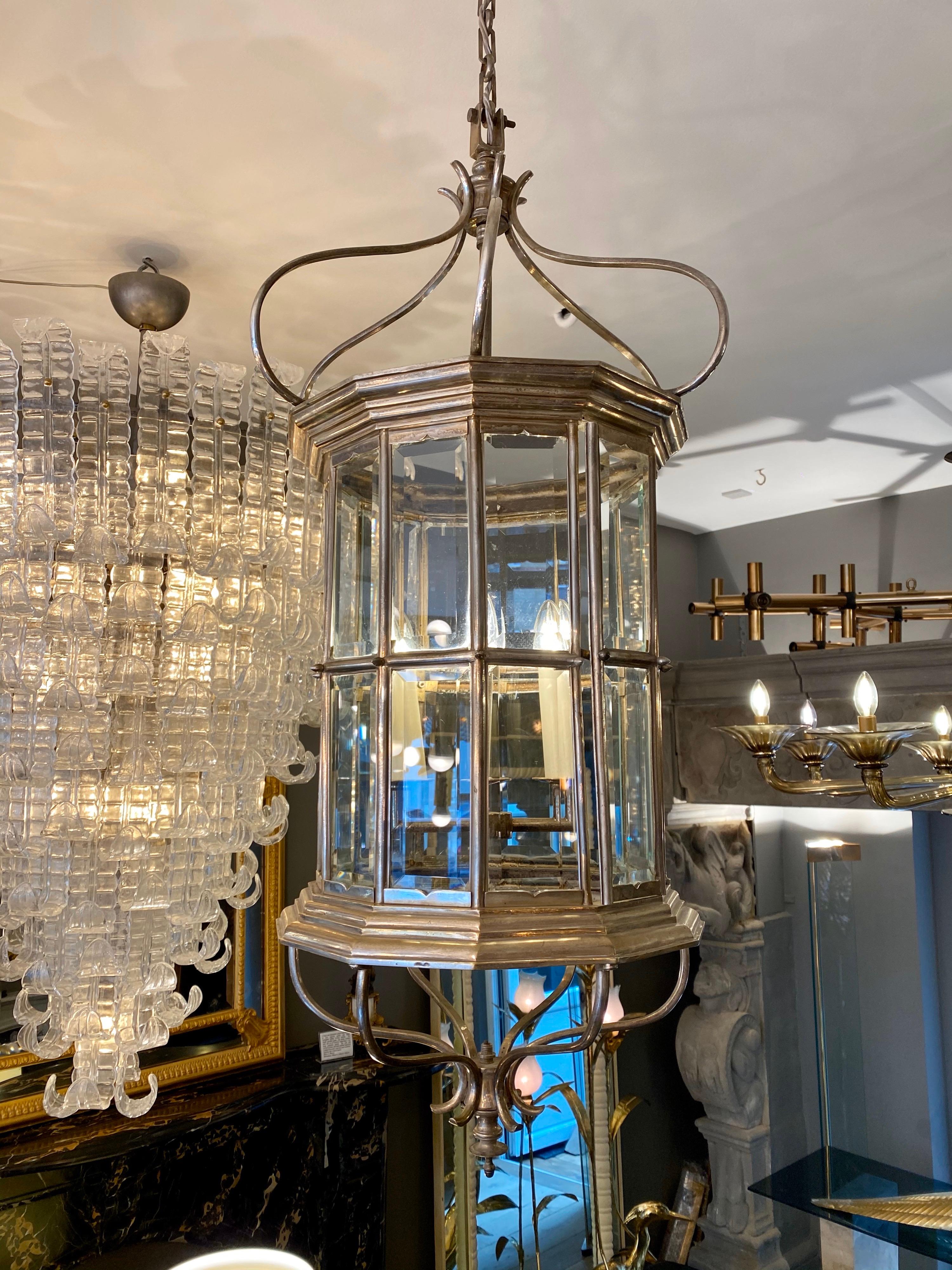 A large French nickel-plated lantern, with 4 light fittings, scrolling canopy and stepped framework. Twelve sided with 24 beveled pieces of glass, with door and catch to access interior. Included is 2.5 meters of chain and ceiling rose.