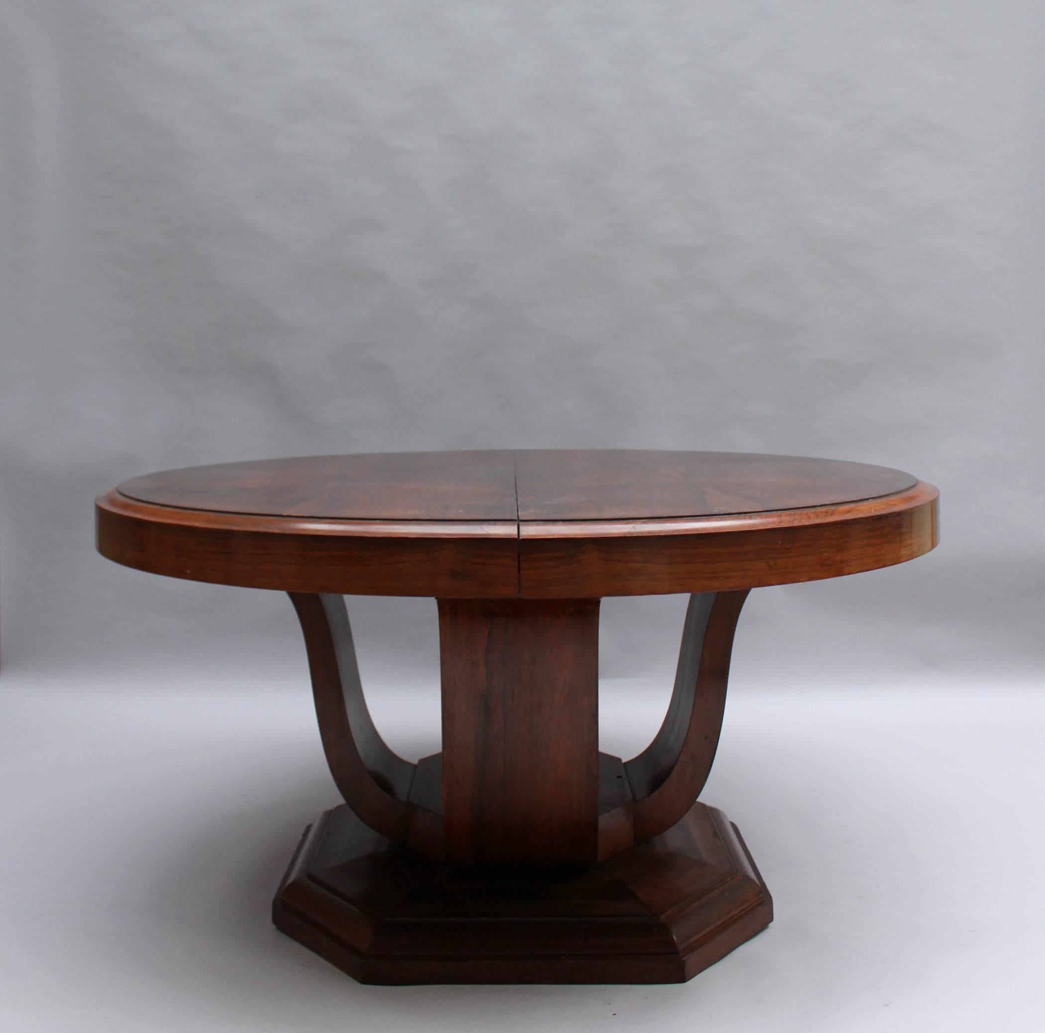 In rosewood, with a lyre-shape pedestal standing on an octagonal base, the table opens in the middle to receive six original center leaves in raw wood with no apron, for a total length of 168 inches / 14 feet.