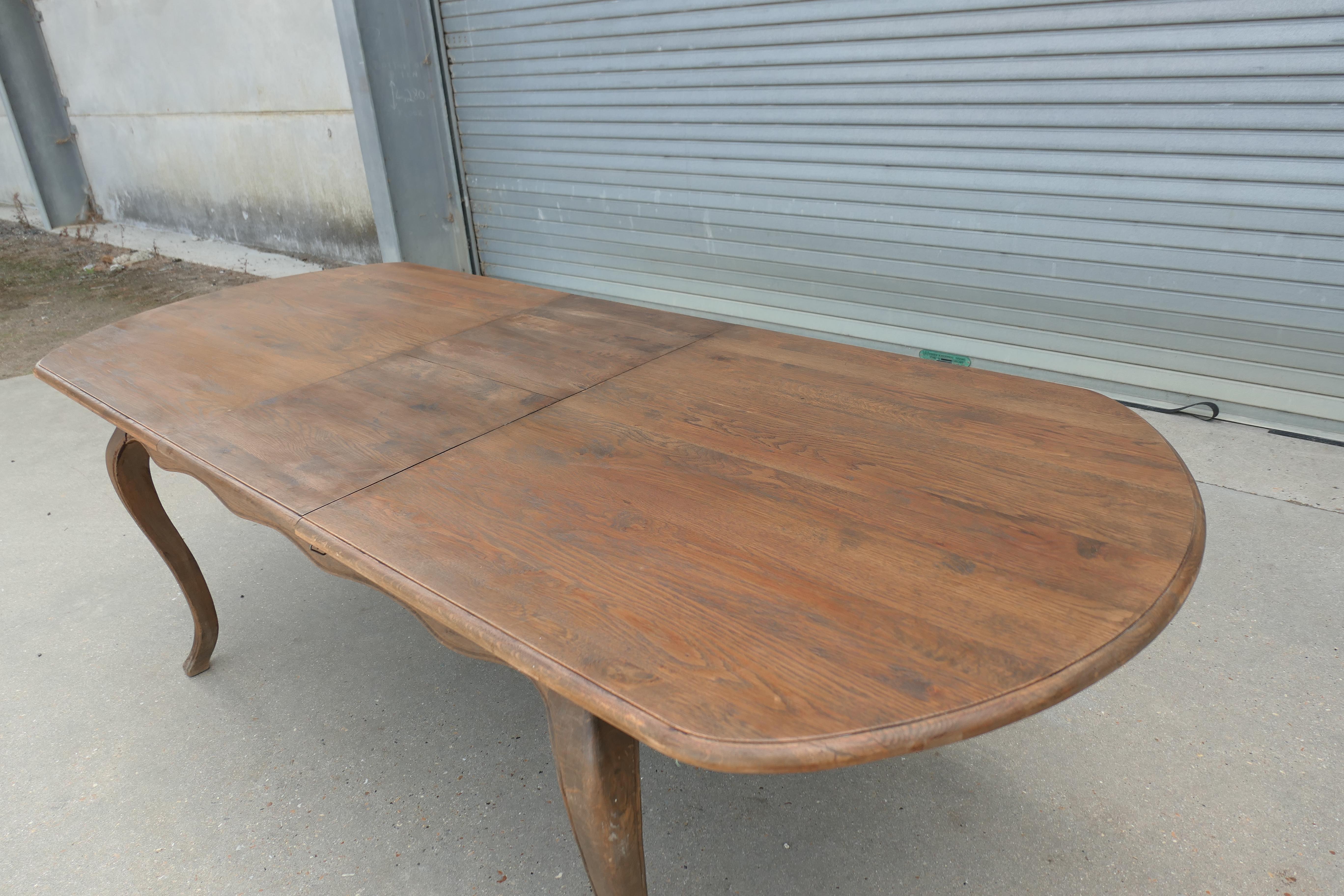 Grande table à manger à rallonge en orme français  

Cette table vient de France : le plateau se déploie en tirant sur chaque extrémité et en laissant le vantail central sortir du centre, il est ensuite repoussé et fixé par de petits clips en