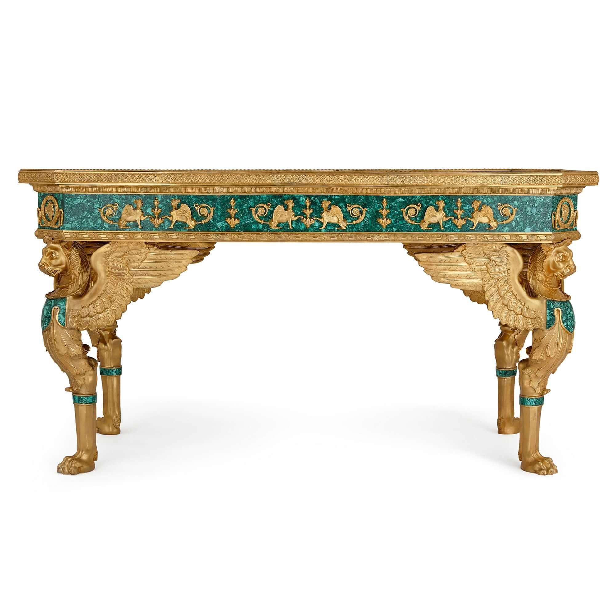 A large French Empire style gilt-bronze and malachite centre table.
French, 20th century.
Height: 85cm, width: 160cm, depth: 79cm

This superb table, a grand and highly impressive object, is a French Empire style table made of ormolu and
