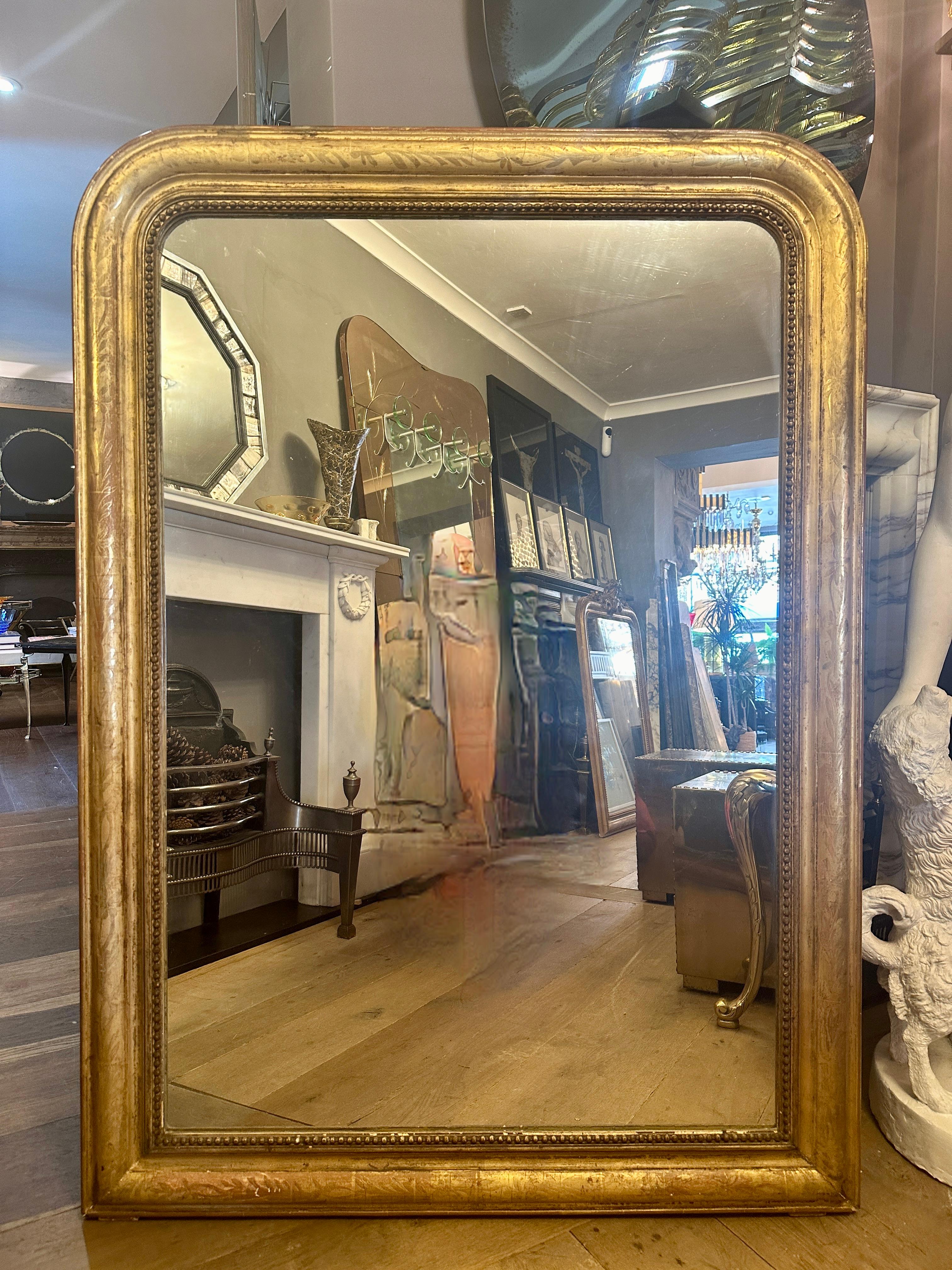 Un grand miroir Louis Philippe du milieu du 19ème siècle, avec un couvercle en forme de dôme. Le cadre est orné d'un travail floral doré et d'une plaque intérieure perlée. La plaque de verre d'origine a été conservée et présente de légères rousseurs