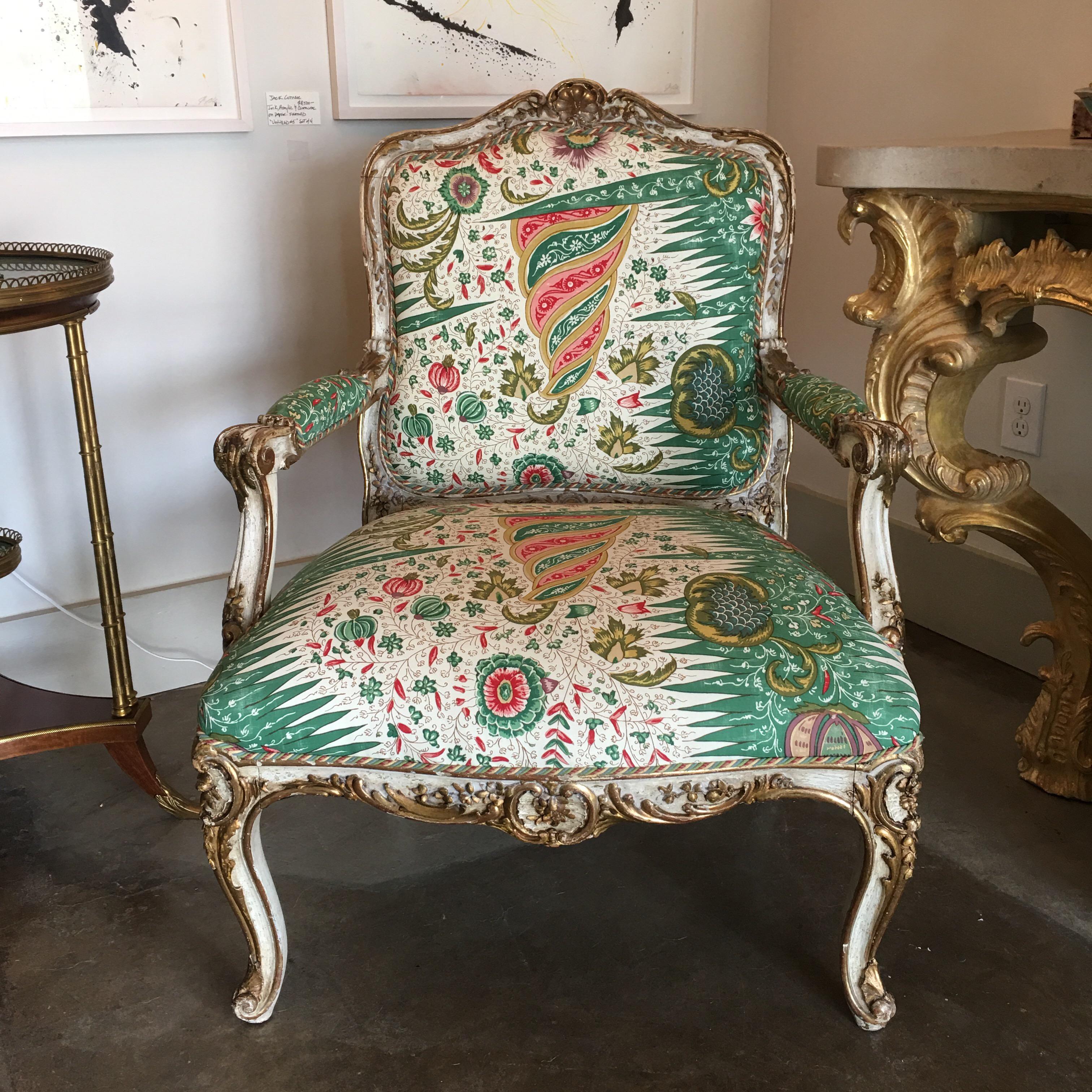 A large French Louis XV style fauteuil with a painting and parcel gilt finish. This comfortable arm chair is the perfect size to be used as a lounge chair in your space, The beautiful carved chair is painted white with gilded accents. The chair has