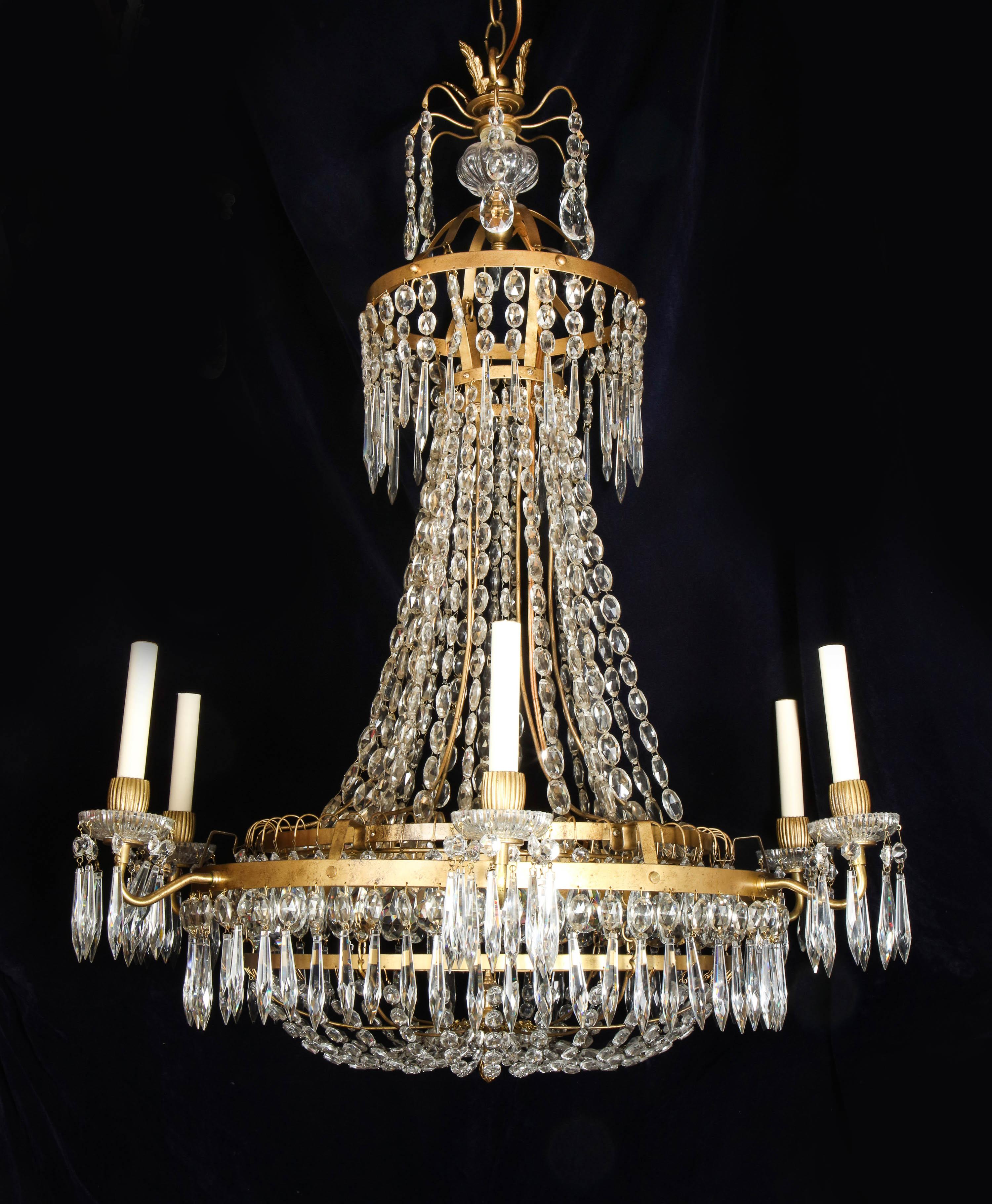This stately Large French Neoclassical style chandelier radiates a refined elegance rooted in late 18th to early 19th-century design, seamlessly marrying architectural balance with the rich ornamentation of Empire-era grandeur. Suspended from a