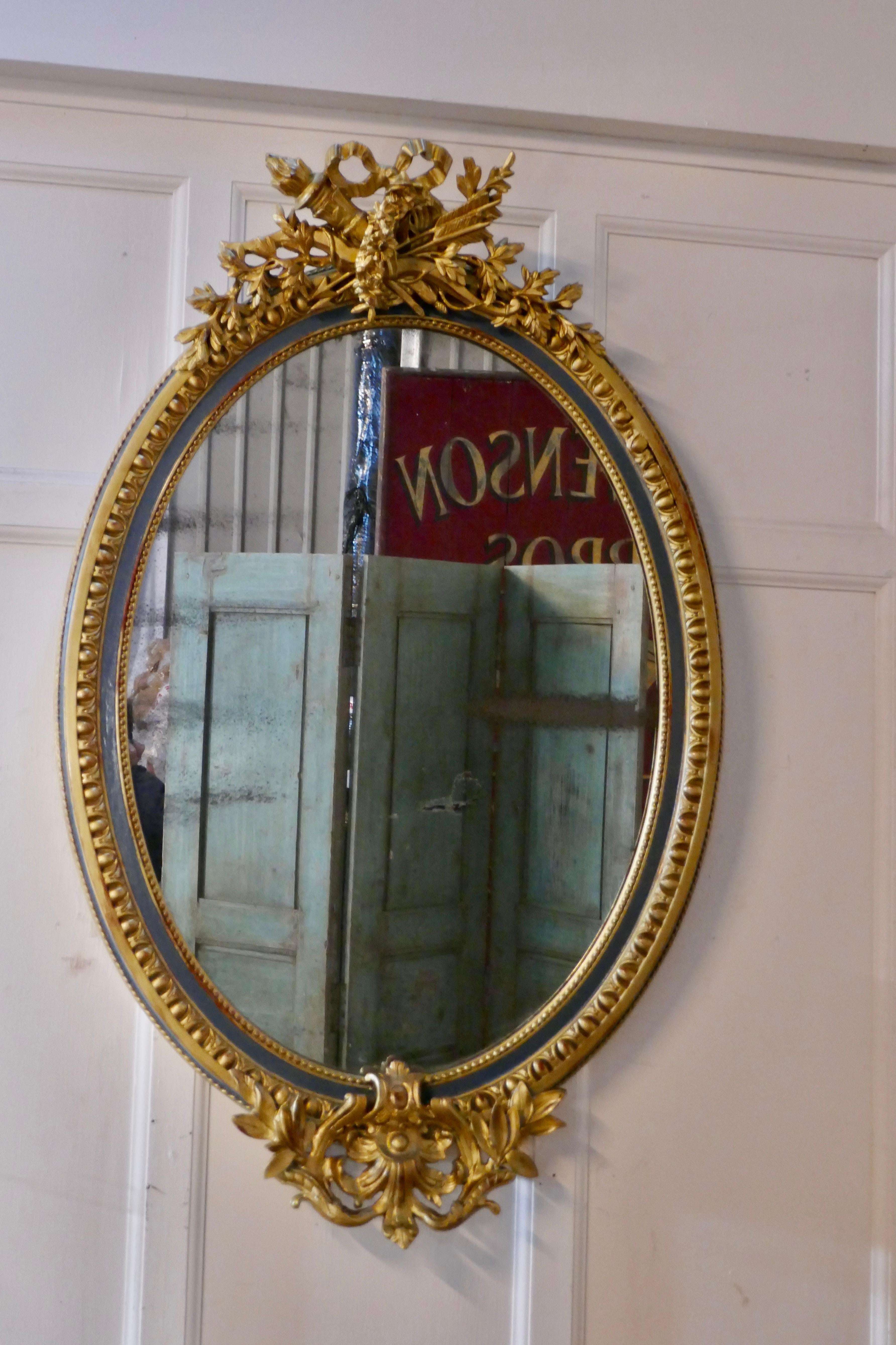 A large French Rococo oval gilt wall mirror

The mirror has an exquisite gilt frame in the Rococo style, it is decorated with arrows and quiver, and many flowers and leaves with an attractive patterned border. In the border there are 2 bands of
