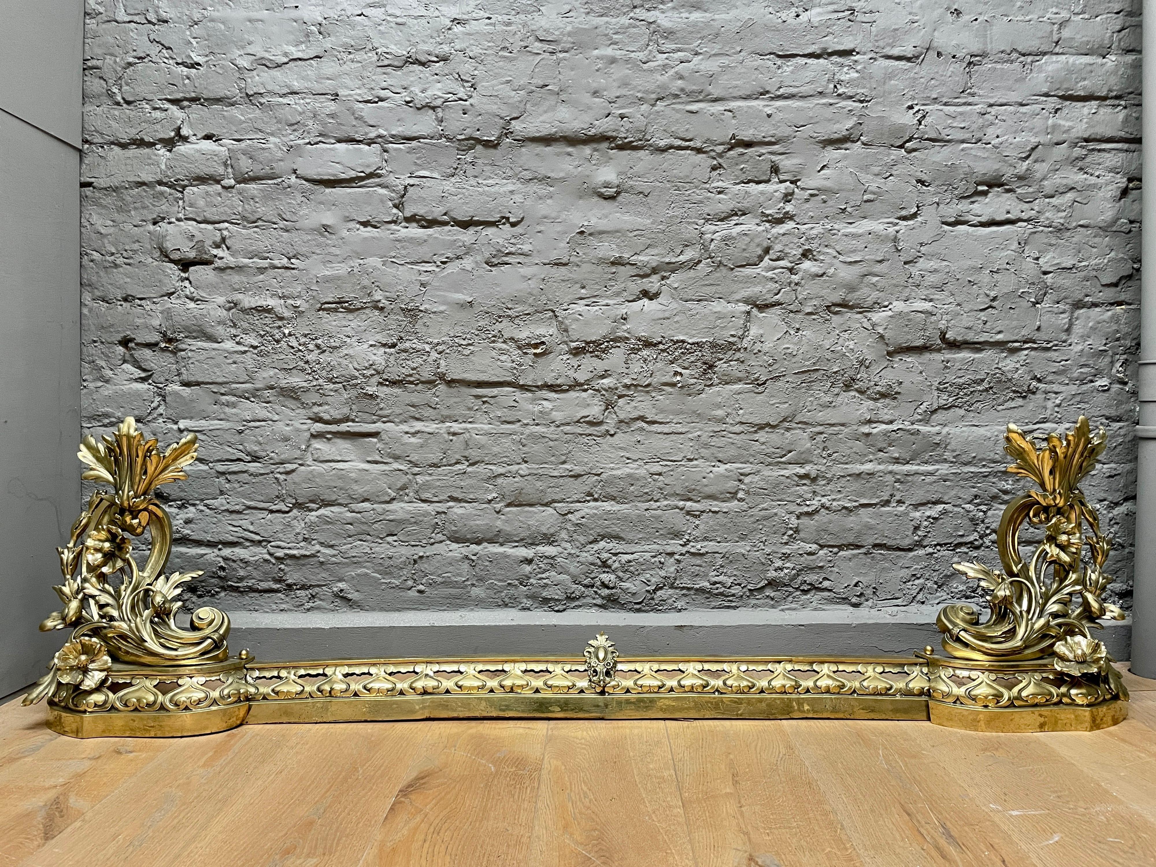 An ornate Rococo style brass fender, the linking bar flanked by tall decorative chenets with fire tool supports to rear. Late 19th C France.