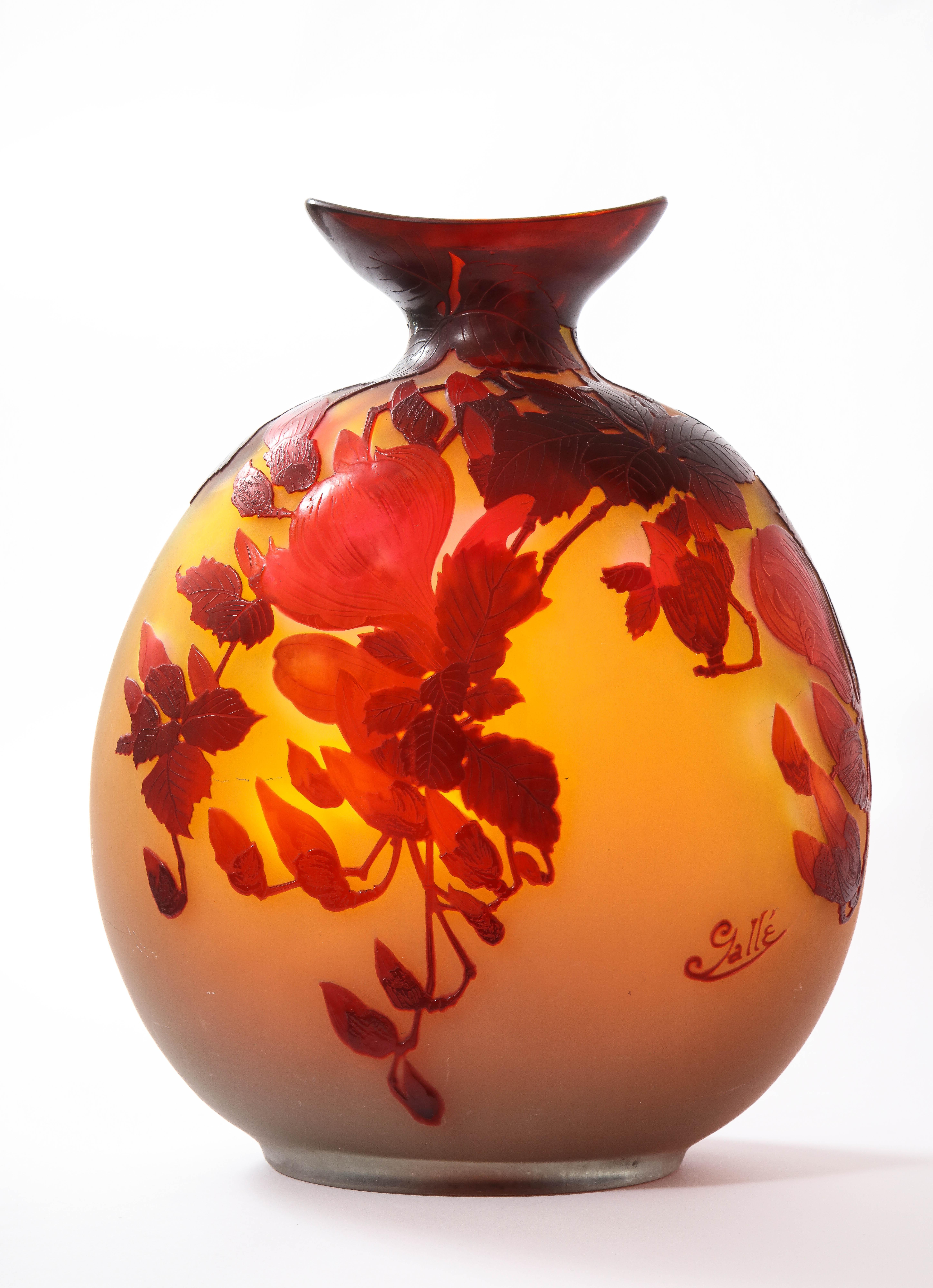 Ce vase en verre d'art camée, poli au sable, du célèbre maître de l'Art nouveau Émile Gallé, est composé d'un magnifique ensemble de fleurs, de feuilles et de branches obtenues par la technique du soufflé, dans des tons de rouge, d'orange et de