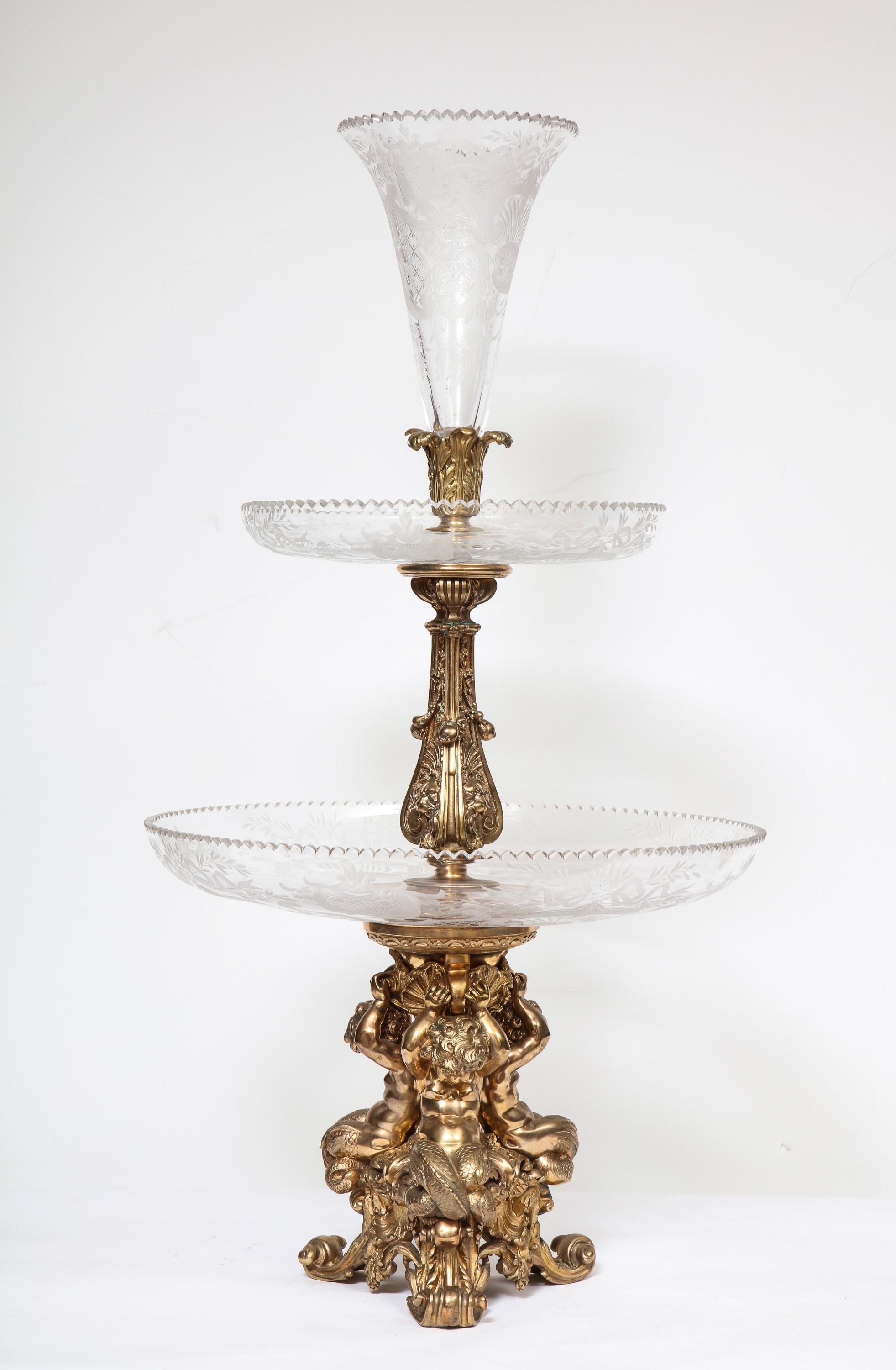 A large French silvered bronze & cut crystal allegorical three-tier centerpiece, attributed to Christofle Paris, circa 1880.

Cast with three seated silvered bronze putti holding the large and impressive three tier etched glass plates and fluted