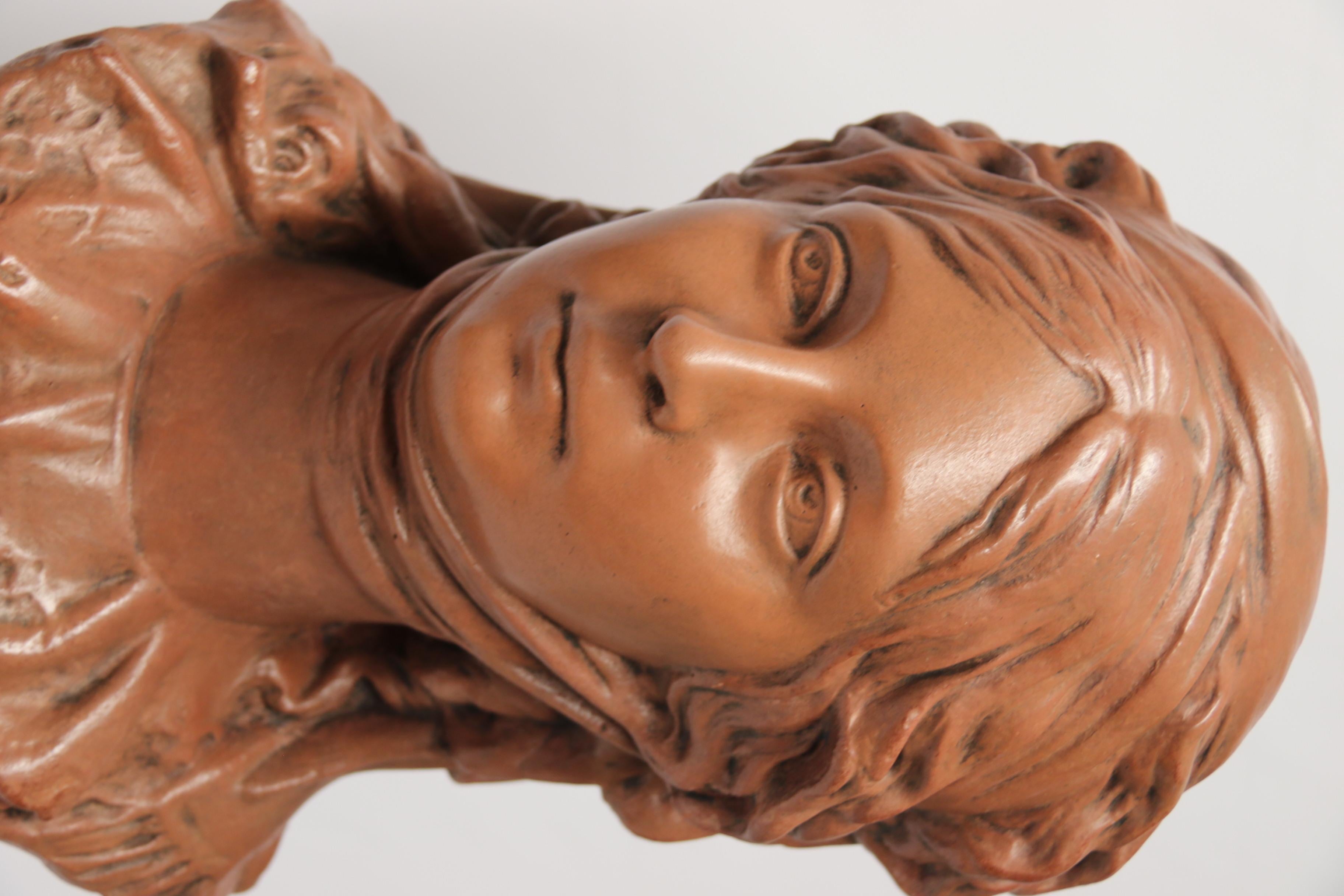 A good decorative French terracotta life size bust of a beautiful medieval maiden wearing a head scarf and showing a lace neckline is mounted and displayed on a turned and moulded mahogany stand with an inset top to the locate the terracotta bust.