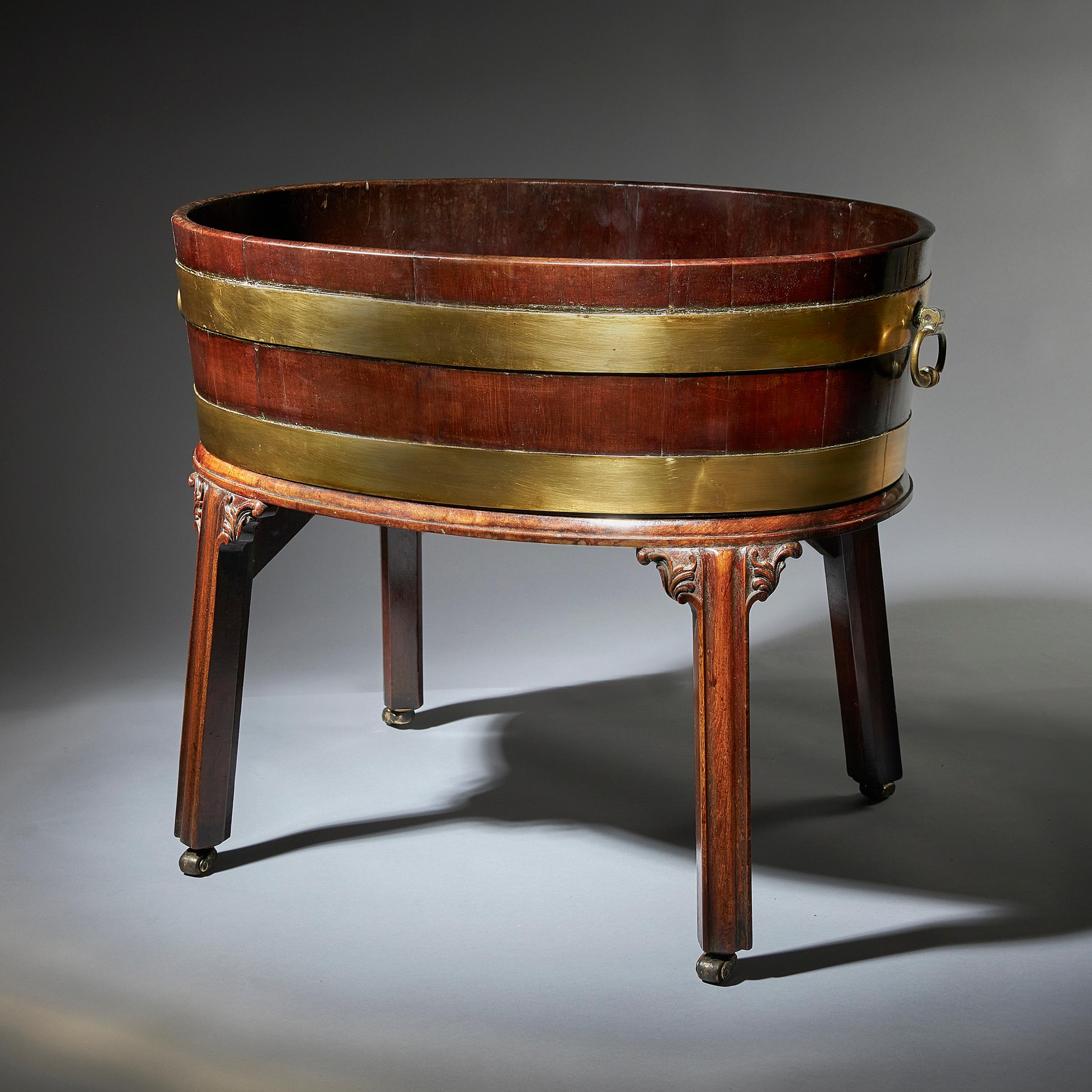 A fine and large mid-18th century George III oval mahogany cellarette or wine cooler on original stand in the manner of Thomas Chippendale. 

Raised on four moulded outswept legs fitted with casters and carved ears of acanthus. The oval body of