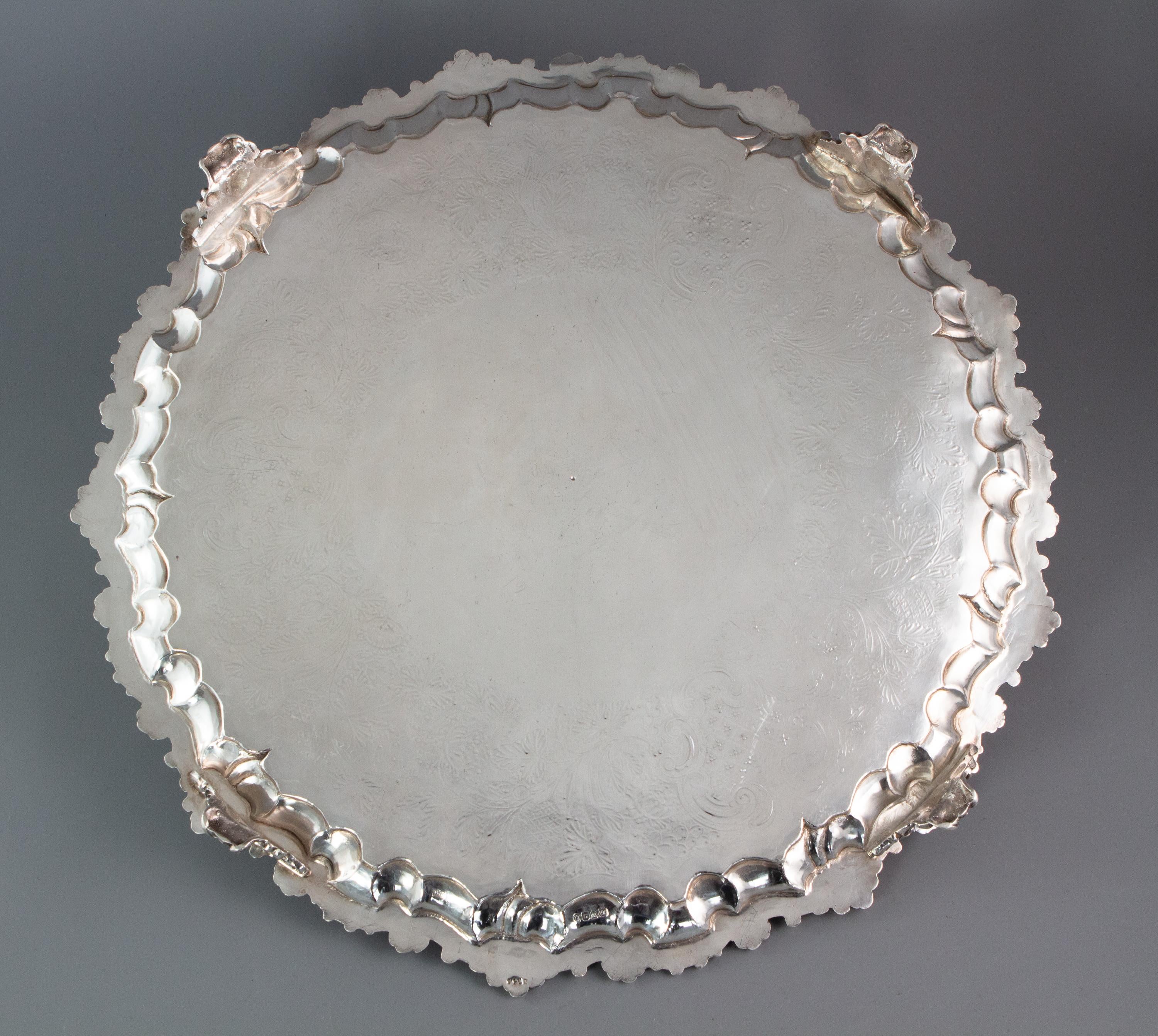 An impressive Georgian silver salver of large proportion. Of circular form with a cast and applied edge decorated with scrolls and shell patterns. The central reserve surrounded by intricately worked ground upon which bright cut flowers, leaves,