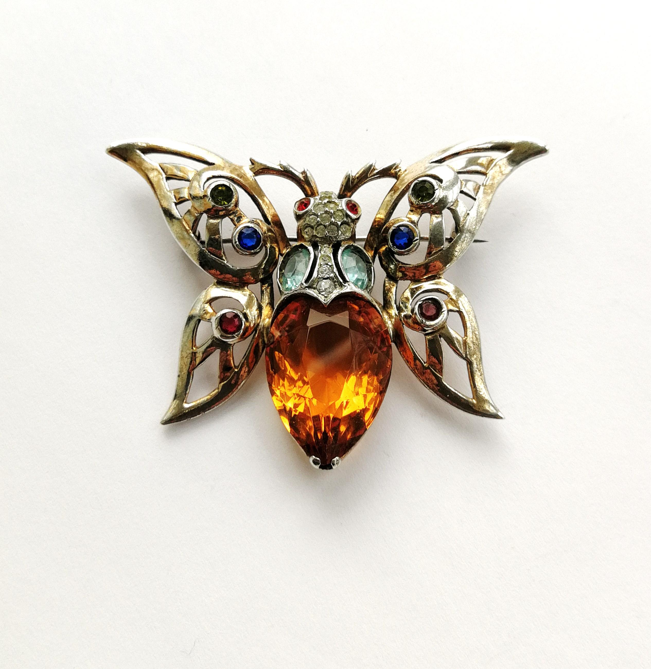A very striking sterling brooch of a butterfly, with a large topaz paste 'body' and other clear and coloured pastes, highlighting the open wings, all set in sterling silver with a soft rose coloured gold wash. Highly typical of costume jewellery of
