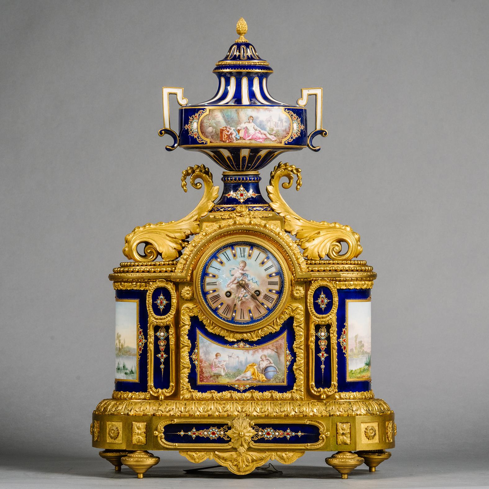 A Large Gilt-Bronze and Sèvres Style Cobalt Blue Ground Porcelain Three-Piece Clock Garniture. 

Comprising a mantle clock and a pair of vases and covers. The mantel clock modelled with a two-handle neoclassical vase above a rectangular base fronted