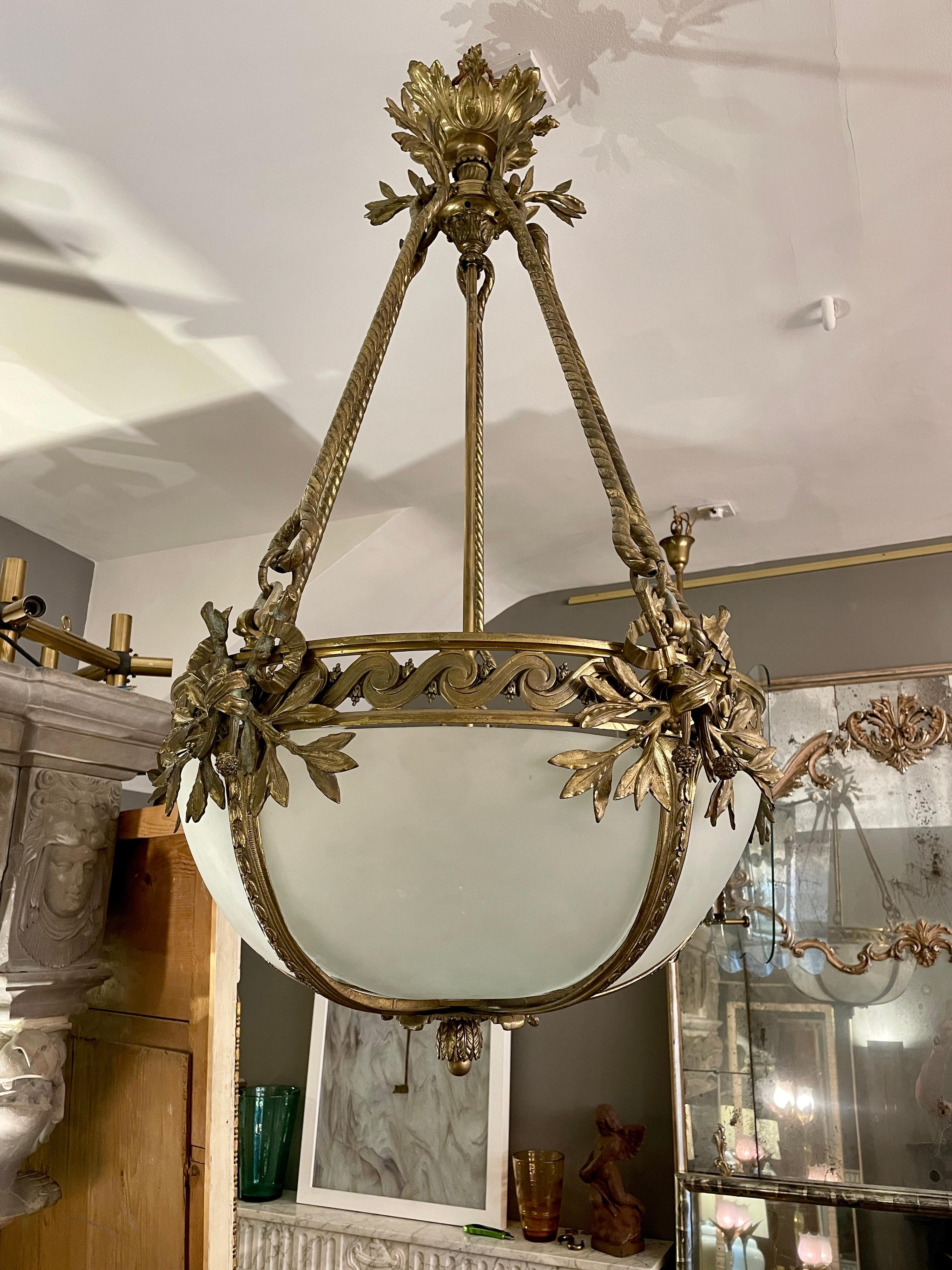 Un grande lampadario o plafonnier in bronzo dorato, molto ben fuso, risalente alla fine del XIX secolo o all'inizio del XX. Il grande rosone a foglie d'acanto sospende cinque barre di corda, che a loro volta sostengono una coppa segmentata in bronzo