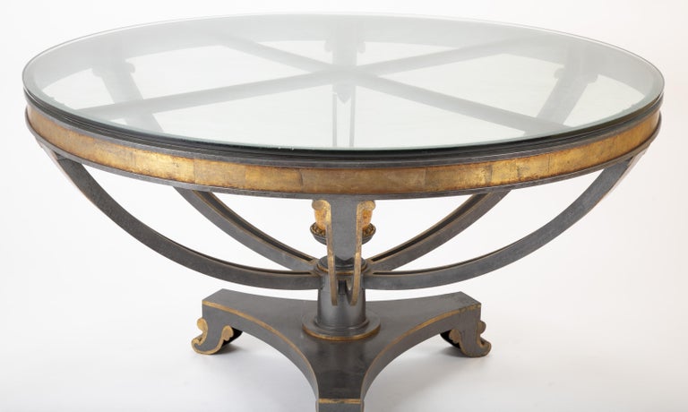 An exceptionally large glass top patinated steel centre table with parcel gilt and faux bois details.