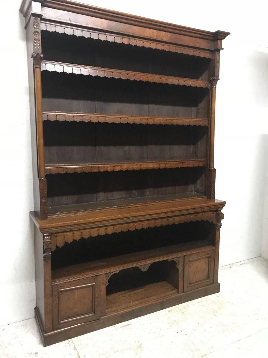 In the style of A W N Pugin probably made by Gillows.
A large cavernous good quality Gothic Revival oak and burr oak bookcase.
The upper section with subtle carved floral details and Corinthian columns to each upper side. Each shelf with leaf style