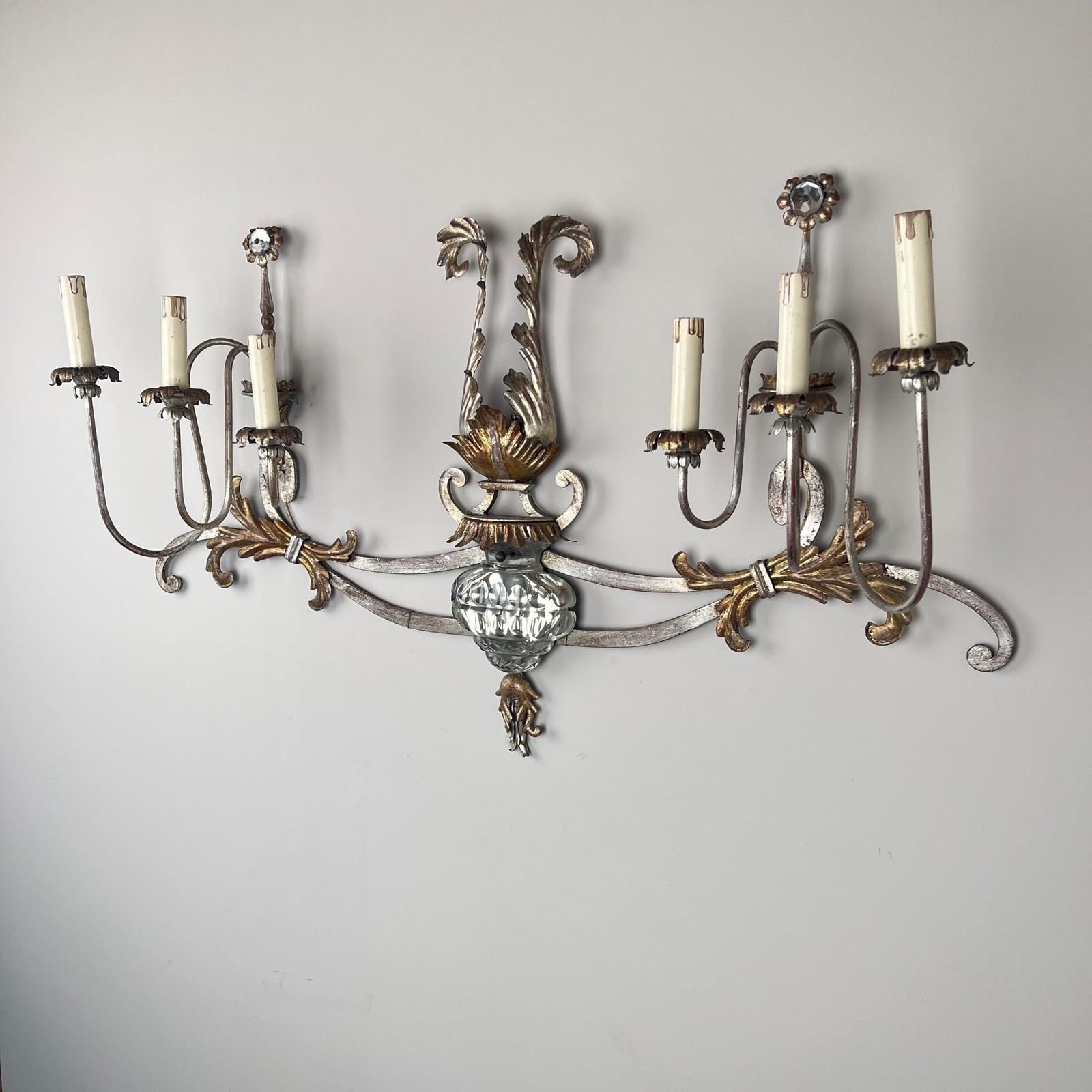 Nel fascino del vento della Francia, durante il nostro viaggio casuale, abbiamo acquisito un magnifico tesoro: la squisita applique Banci Firenze Silver Gilt. Un pezzo che incarna la grandezza, che misura poco più di un metro di larghezza, ornato da