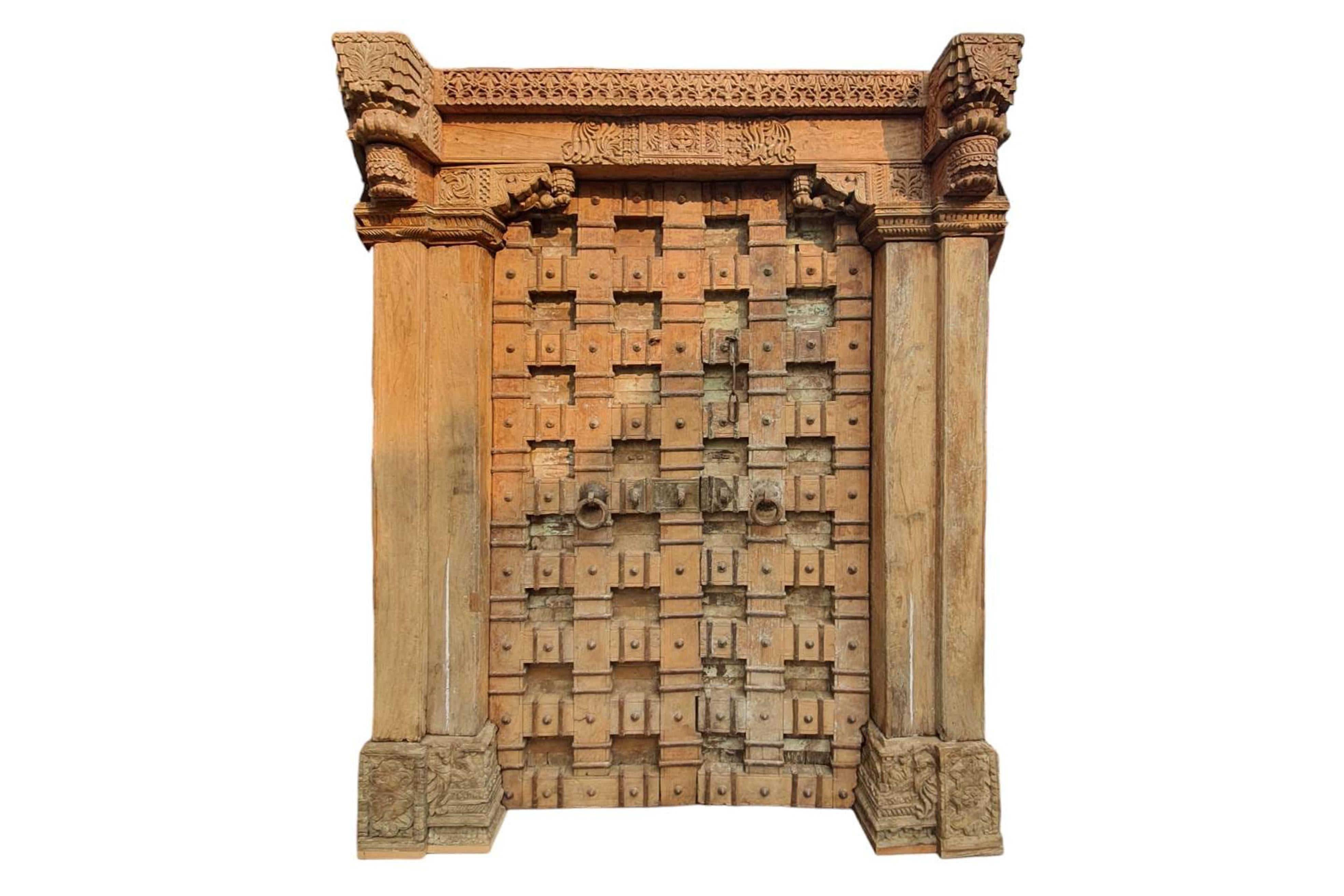 This enormous teakwood entrance door, originally covered in layers of paint, is an excellent example of Indian haveli (mansion) architecture. The upper lintel is exquisitely carved in floral designs, including marigolds, pomegranate, and Champa