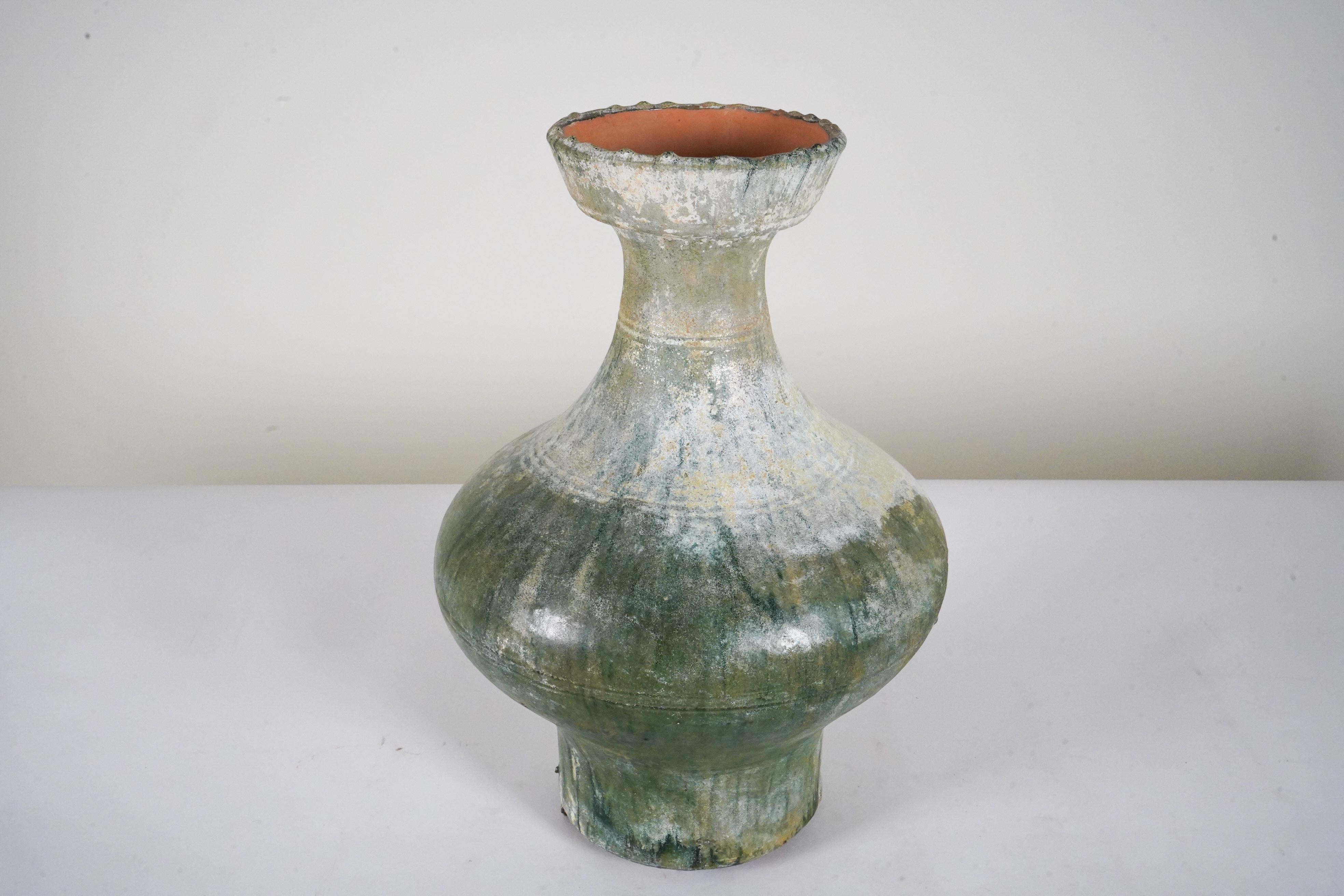 This is a fine example of a Han hu wine storage vessel, buried for the afterlife. The compressed globular body narrows sharply to a slender waisted neck, covered with a dark green lead glaze that has developed a silvery patina due to long-term