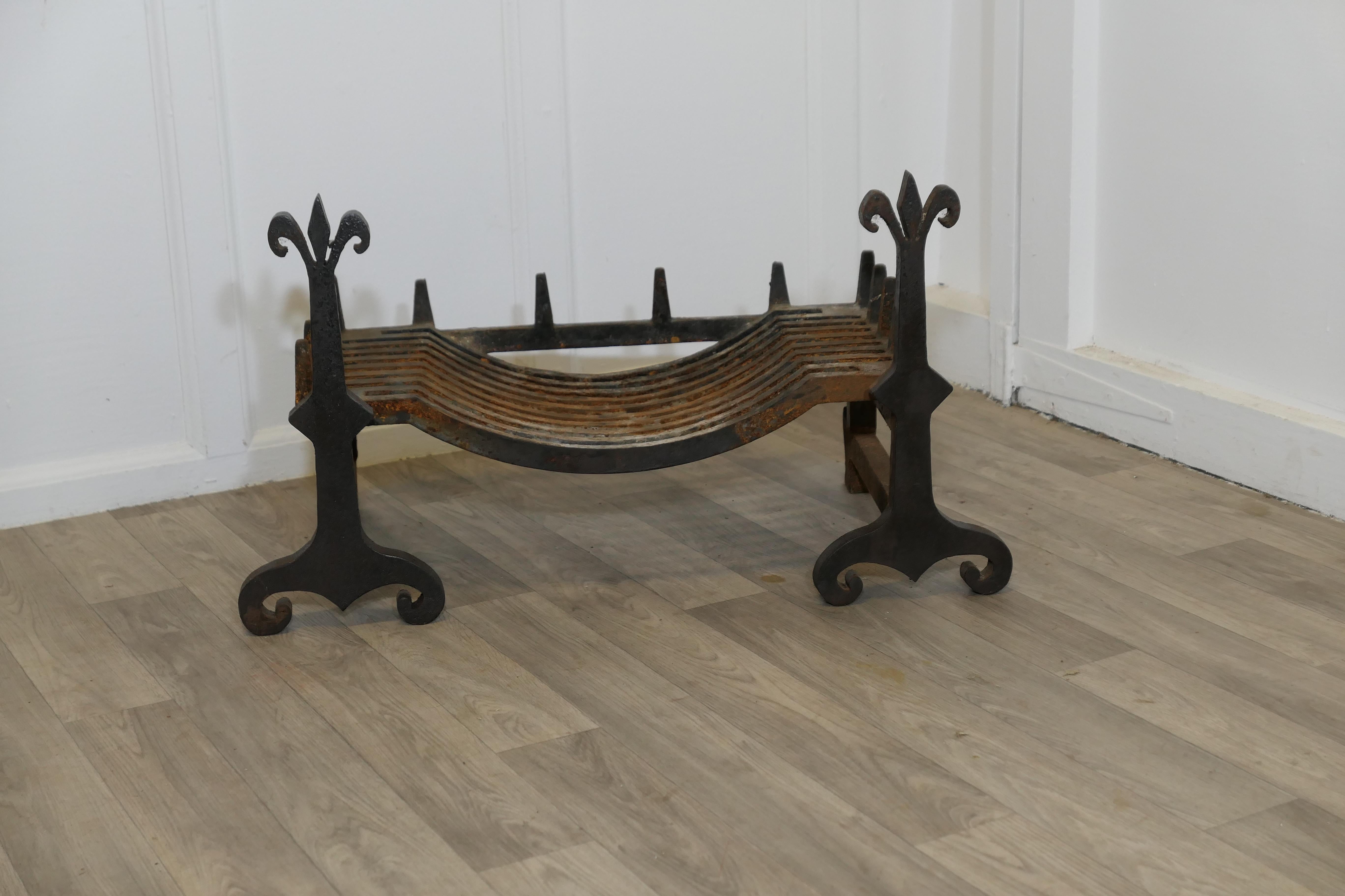 A Large, Heavy Pair of Late 19th Century Iron Andirons Complete with Grate 

This is a Very Heavy pair of Andirons, they are made of cast iron and topped off with a Fleur des  Lys  and have their original large log grate
The Grate is in very good