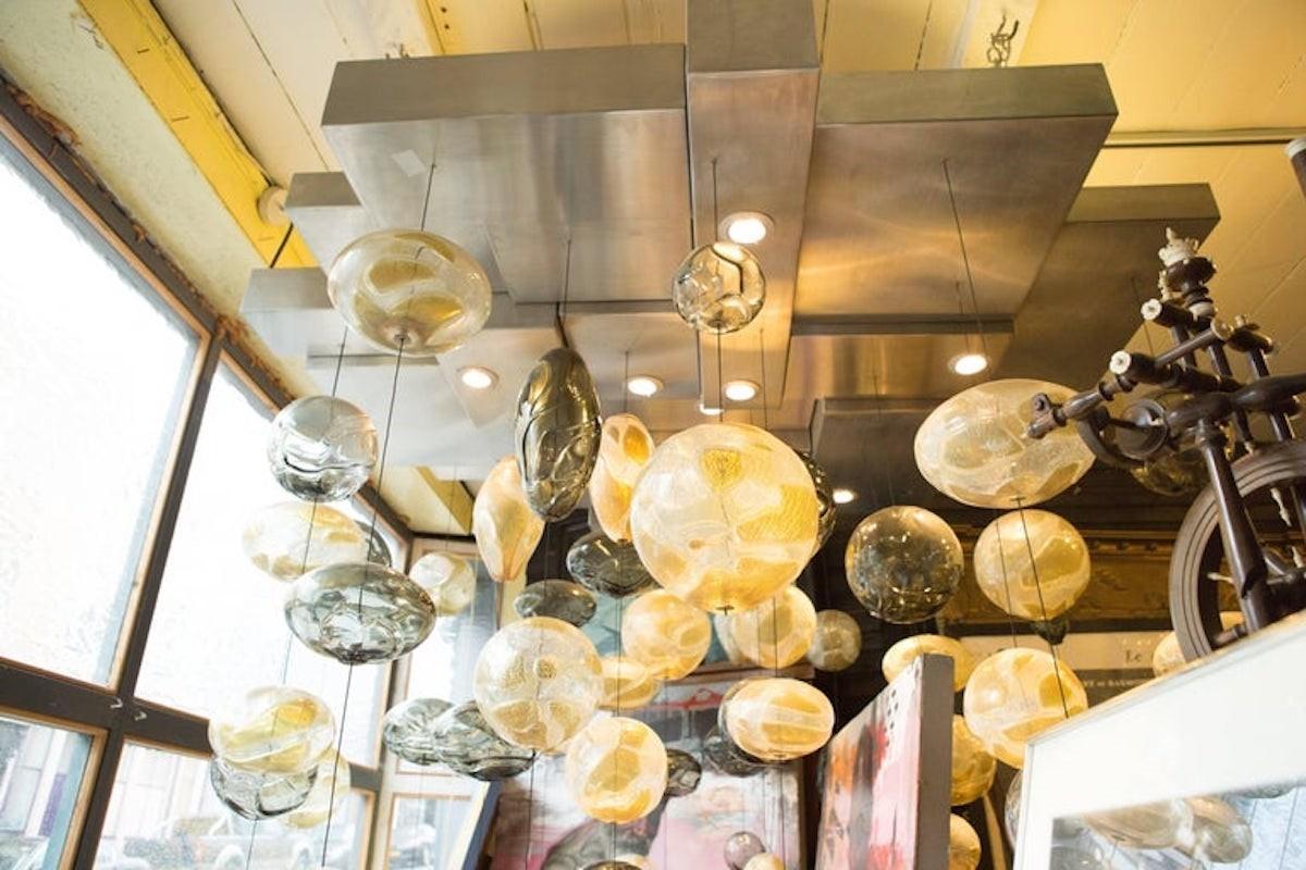 Presenting an exquisite glass light installation that doubles as a masterpiece of artistry. Each glass shade is meticulously handcrafted at Gangbar Studios in Toronto, Canada, showcasing unparalleled craftsmanship and attention to detail. Originally