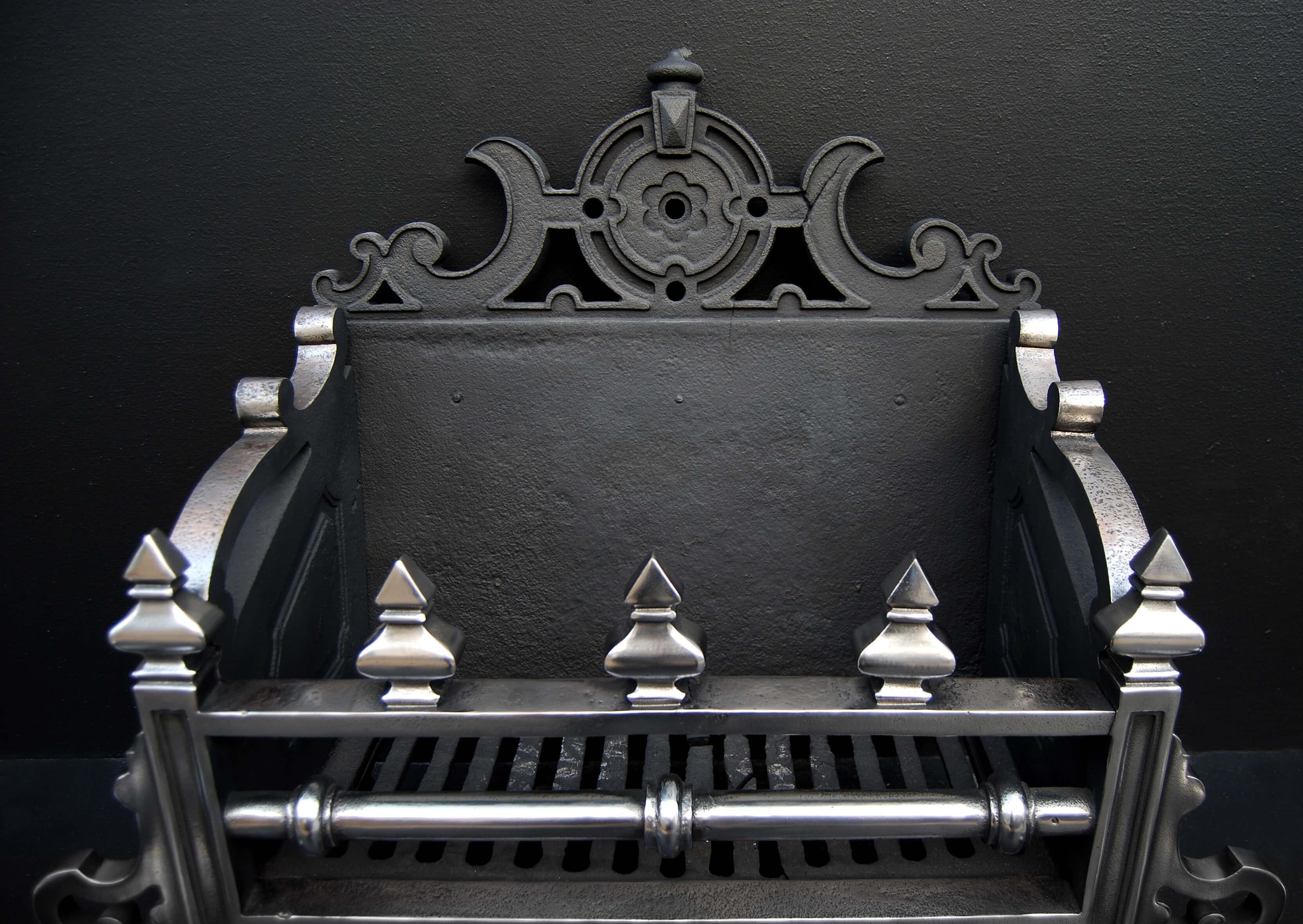 A large and impressive mid 19th century English cast iron firegrate. The polished steel dogs with scrolled feet and bulbous decorative finial. The basket front bars with finials above and below. Decorative shaped and pierced back.

Measures: Width