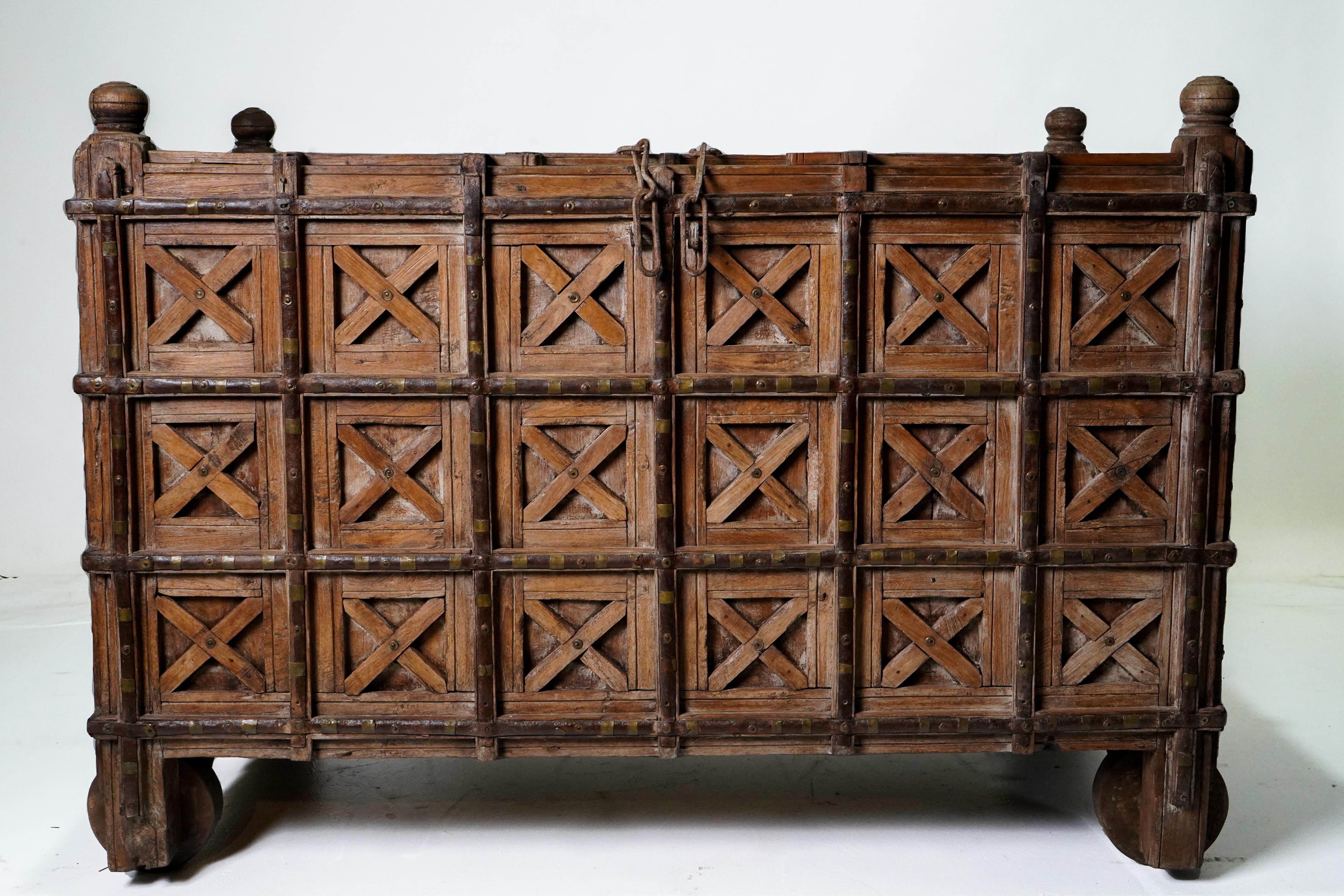 A superb example of an Indian (Gujarat) dowry chest with ornate frame, iron reinforcements and wheels. These chests were used to hold blankets and other valuables. The small upper door could be locked. Chests this large were owned by wealthy people