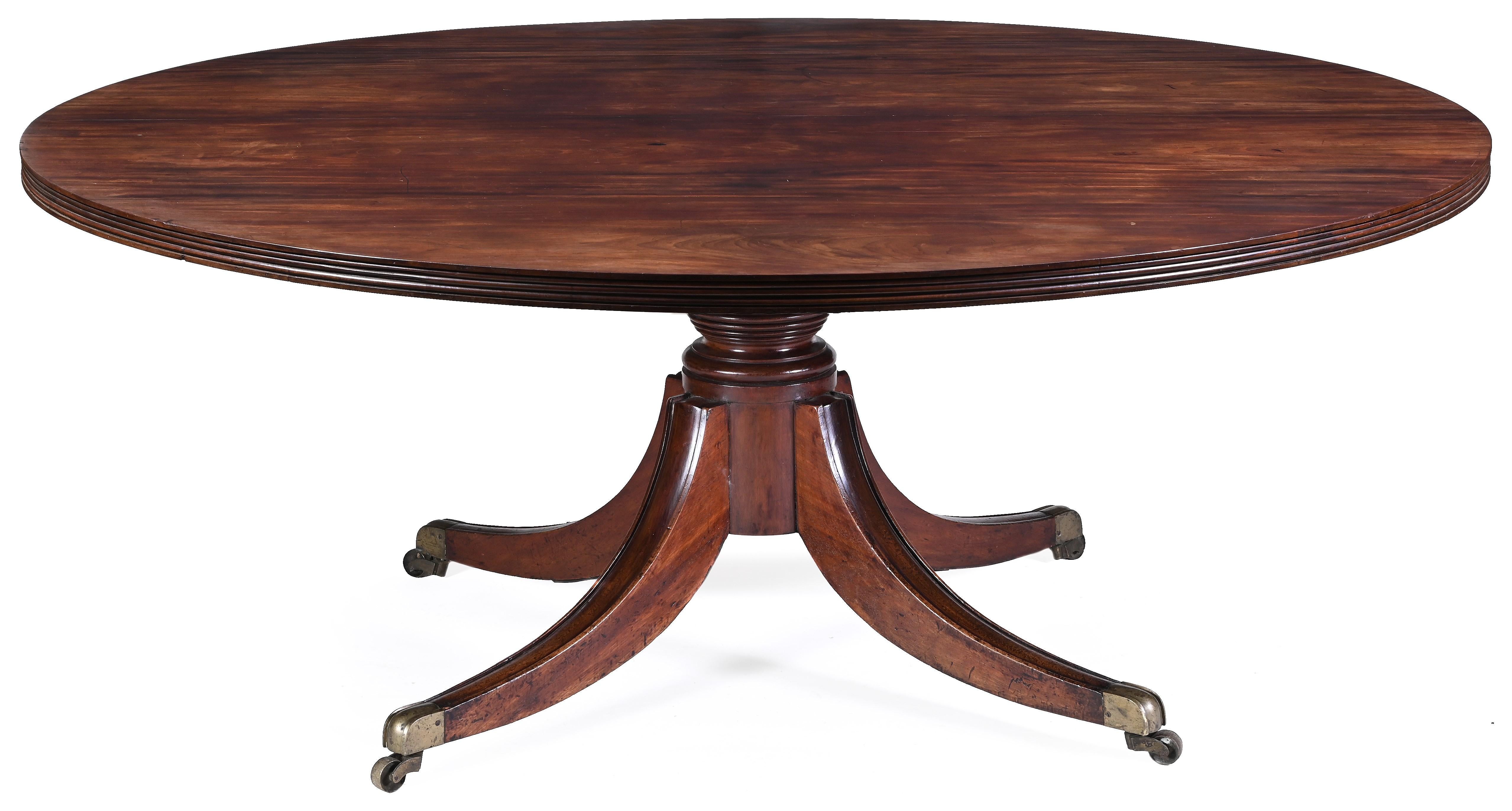 A large Irish Regency mahogany dining table, the well figured mahogany circular top with a double reeded edge, resting on a large turned pillar with four splay reeded sabre legs, terminating in brass lions paw casters. Stamped 3072.

By Mack