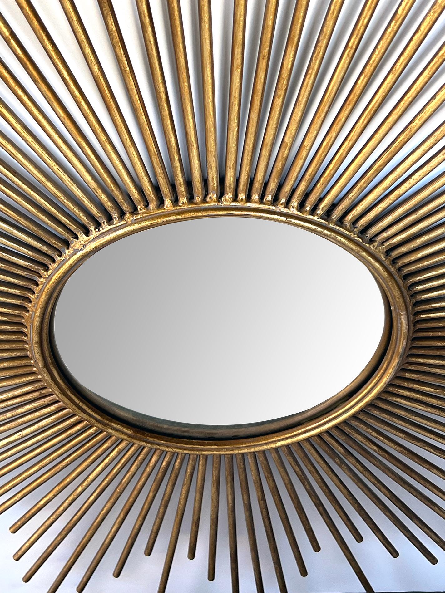 centering a convex mirror within a gilt metal frame consisting of radiating spokes of varying lengths