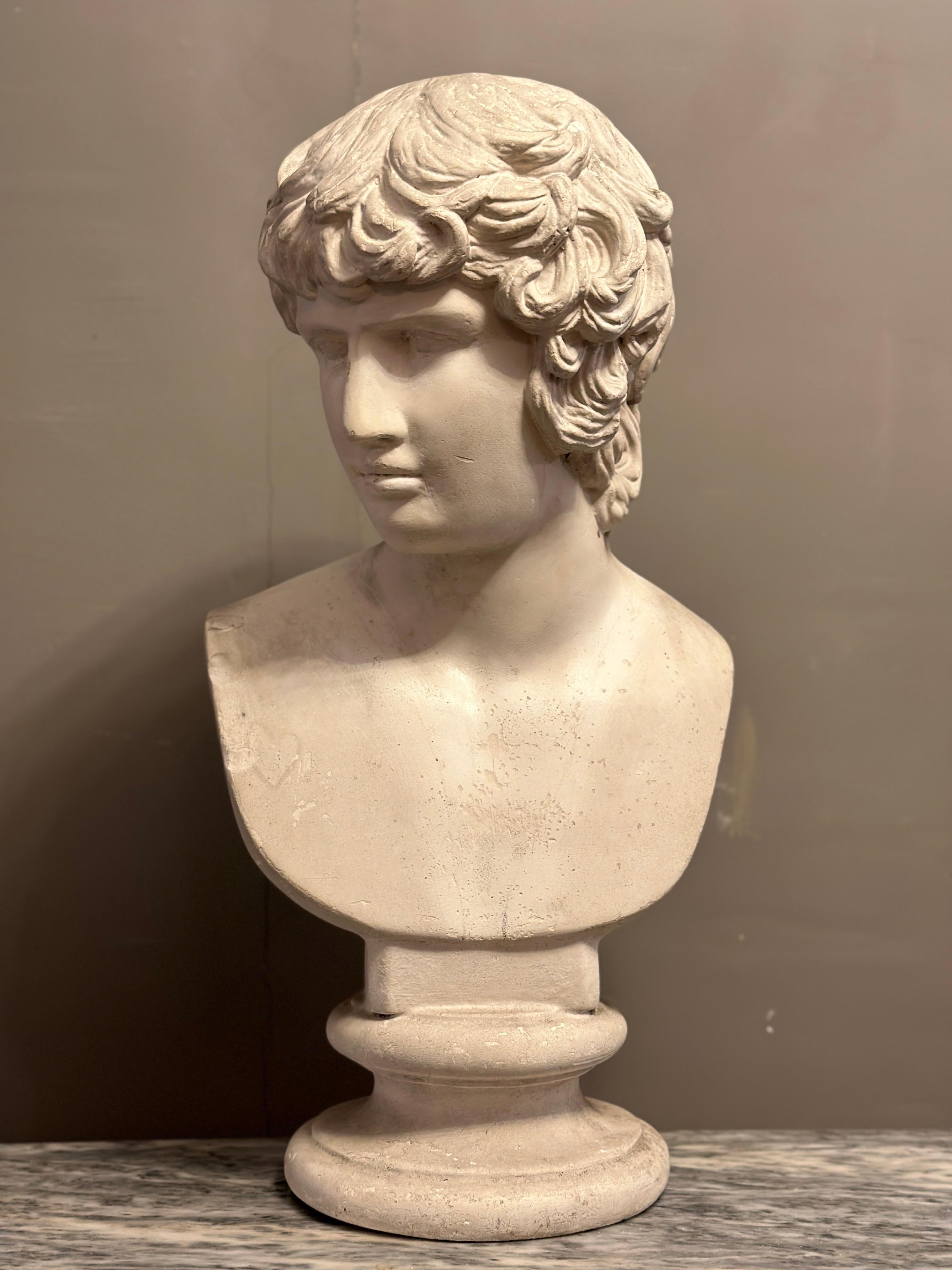 A large life size plaster bust of Alexander in the classical taste. Stood on a circular soccle, classical depiction. Aged and warm patina. Images and video are a true reflection of condition. Dated to turn of the 20th century. One can just make out